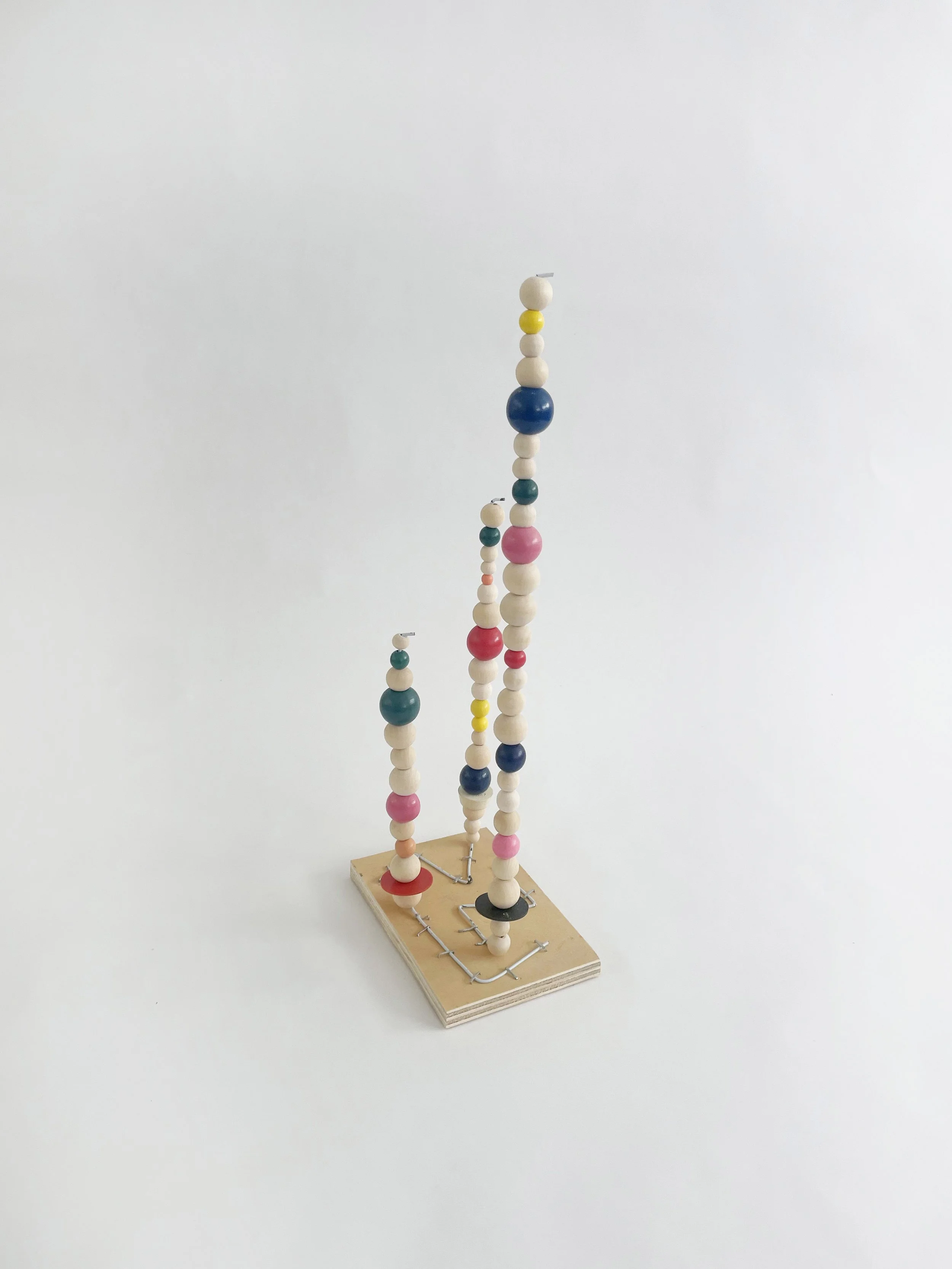 Untitled (watts tower), 2026, 16h x 6w 4d - natural and color wood beads, wire hangers, heavy duty staples, plywood, felt. 
