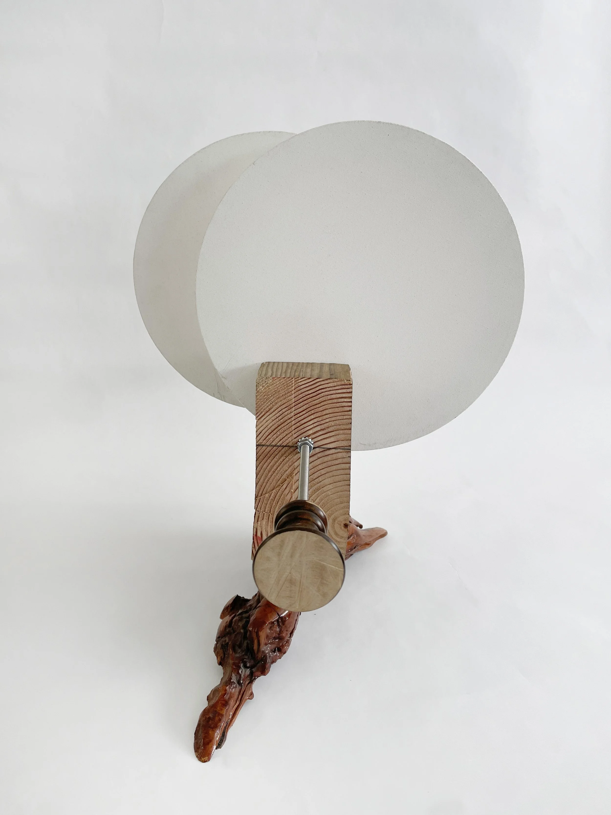 Untitled (two disks) 2025- 2026, 19.5h x 16w x 22d - thrift store resin coated driftwood, 3x7 construction timber, threaded rods, lock nuts, 2 pre-primed round stretched canvas, wood finials, dowels, wood beads.