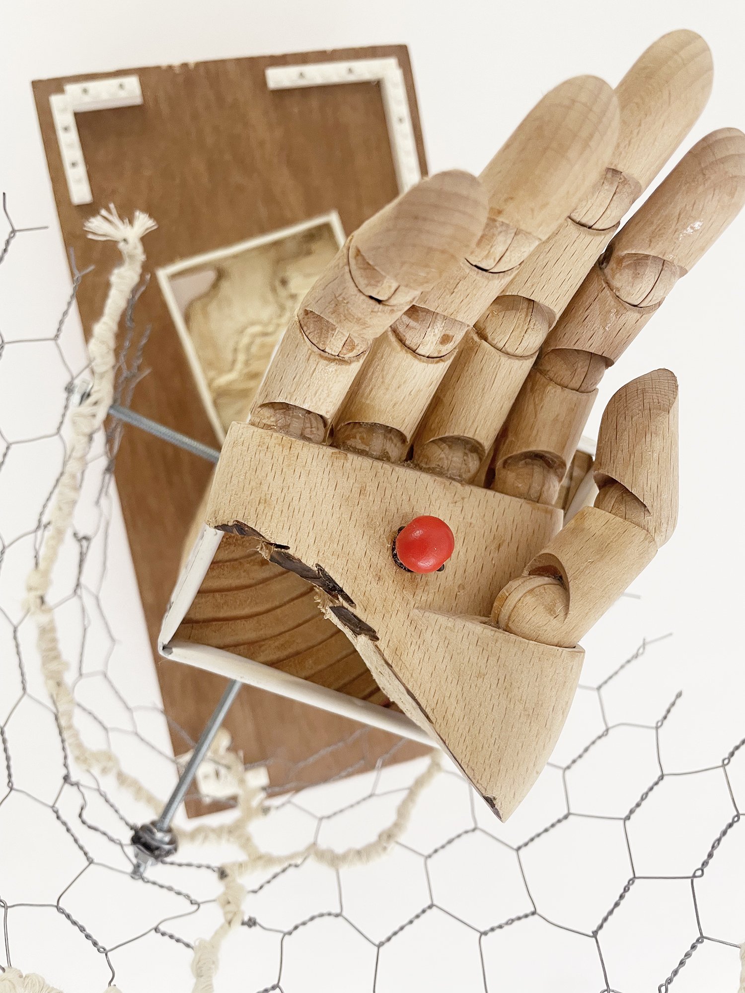 Untitled (Logan's Clock), 2025, 19h x 14w x 14d - salvaged plywood,4x4 lumber, walnut veneer, wood pegs {feet}, Ikea wooden model hand, chicken wire, butcher's string, Ikea metal trim, cotton fabric, threaded metal rod, wood beads, nuts, washers,