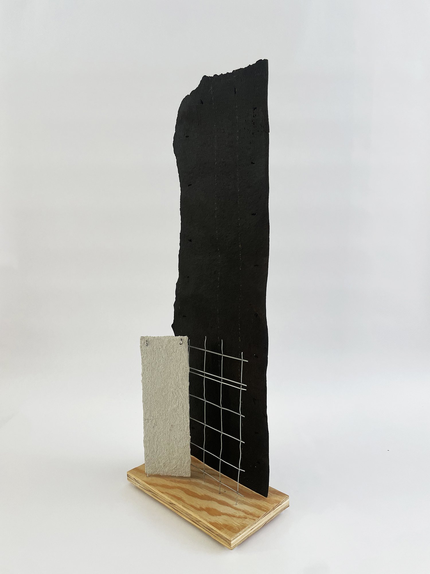 Untitled (Depeche Mode), 2025, 38h x 10w x 5.5d - salvaged plywood, black roofing paper, construction mesh, dry cleaner hanger, paper, acrylic white primer, acrylic coarse pumice gel, aluminum wire, plastic sliders {feet}, polyester thread.