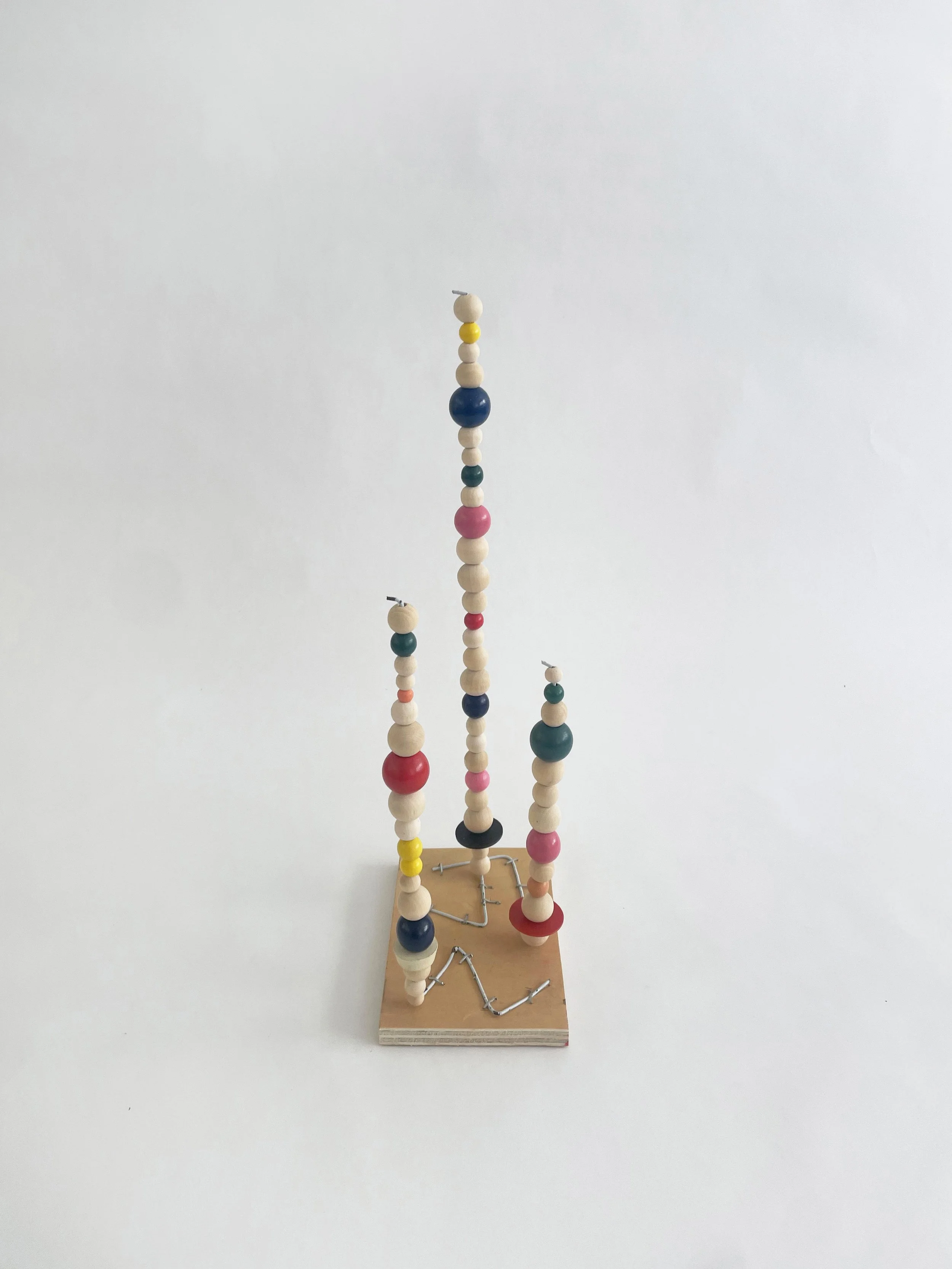 Untitled (watts tower), 2026, 16h x 6w 4d - natural and color wood beads, wire hangers, heavy duty staples, plywood, felt. 
