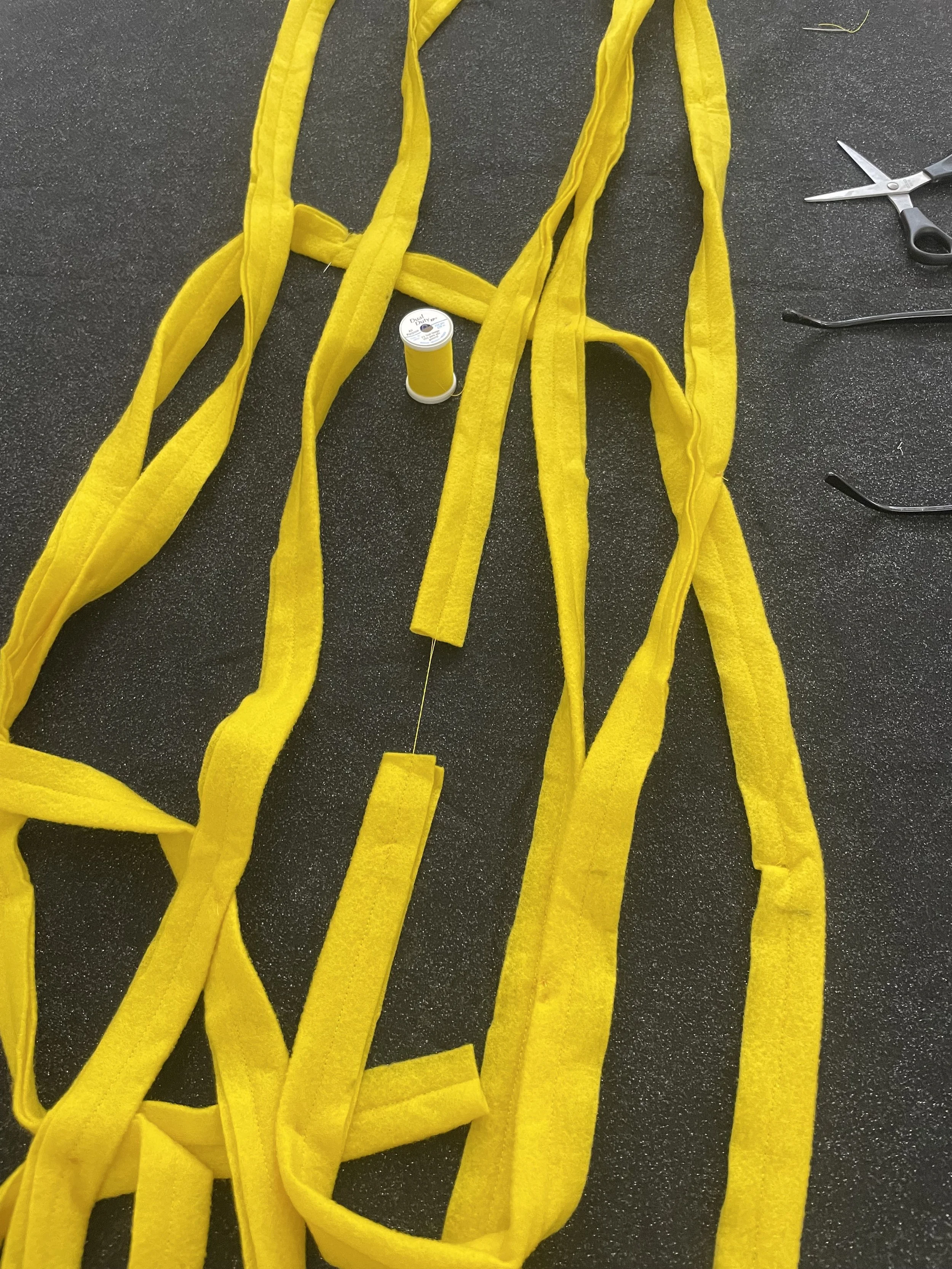Untitled (the spaghetti tapestry), 2018-2026, 8’ x 3’, black sparkle felt, yellow felt, thread, cotton edging. (detail)