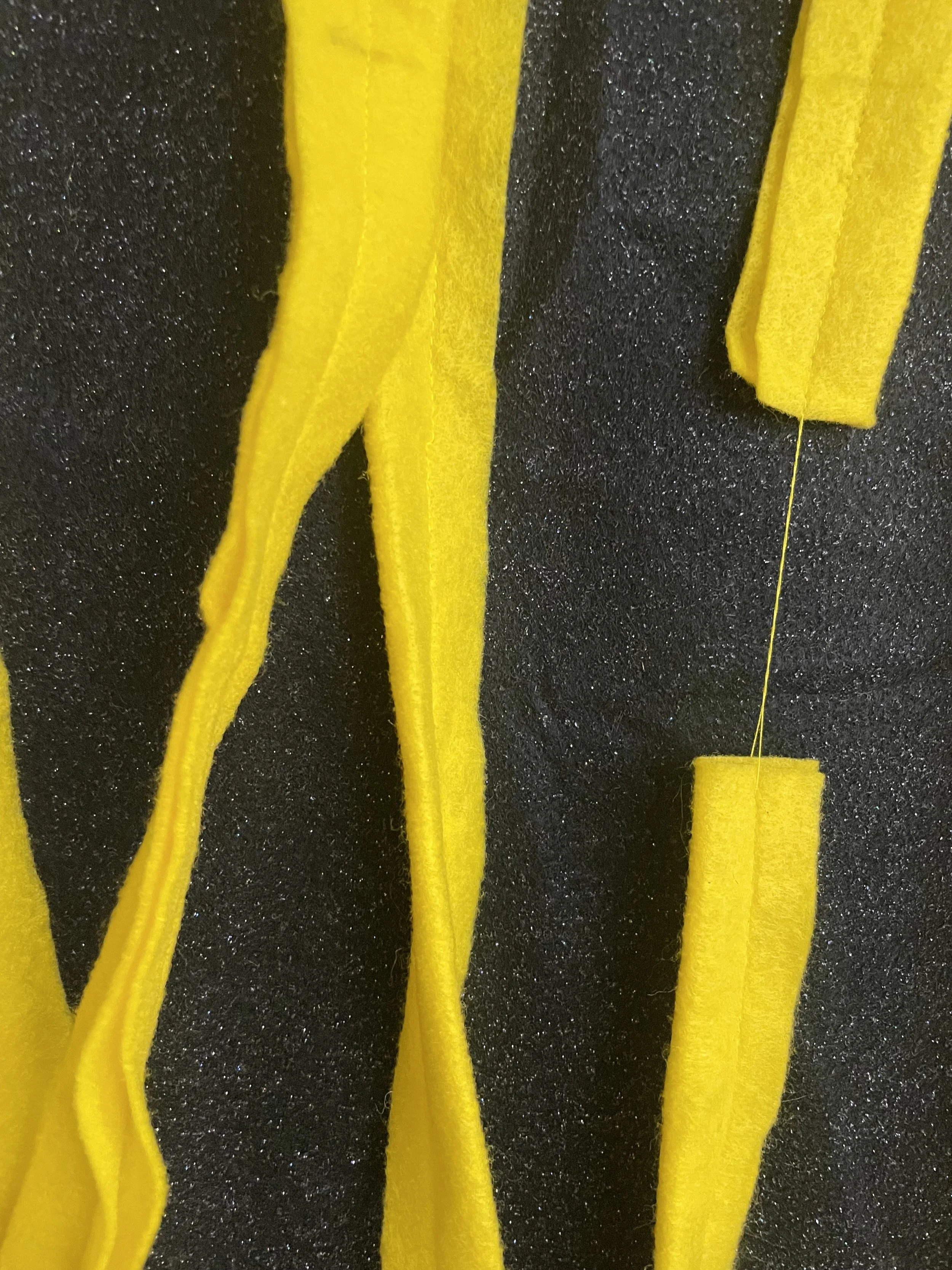 Untitled (the spaghetti tapestry), 2018-2026, 8’ x 3’, black sparkle felt, yellow felt, thread, cotton edging. (detail)
