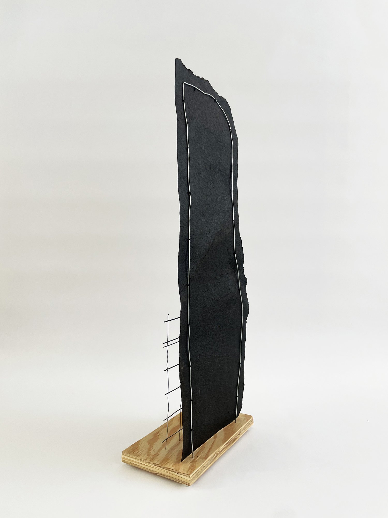 Untitled (Depeche Mode), 2025, 38h x 10w x 5.5d - salvaged plywood, black roofing paper, construction mesh, dry cleaner hanger, paper, acrylic white primer, acrylic coarse pumice gel, aluminum wire, plastic sliders {feet}, polyester thread.
