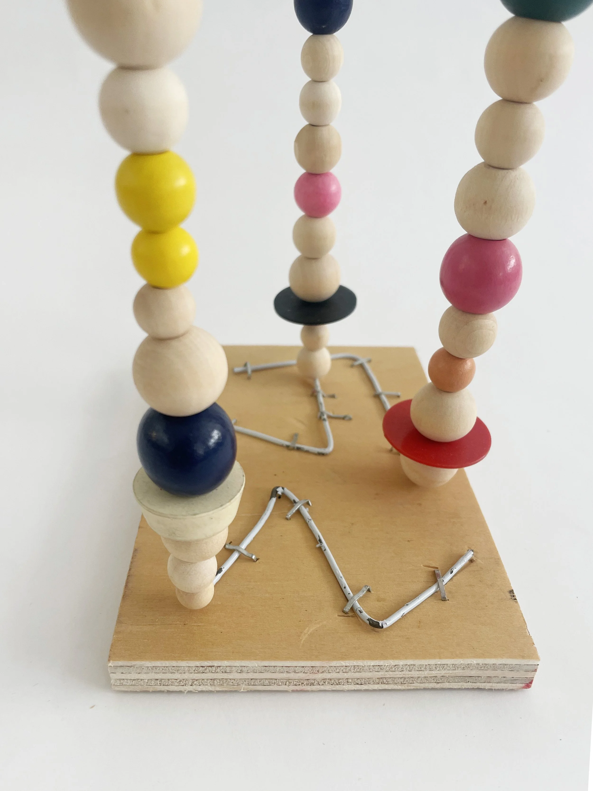 Untitled (watts tower), 2026, 16h x 6w 4d - natural and color wood beads, wire hangers, heavy duty staples, plywood, felt. 