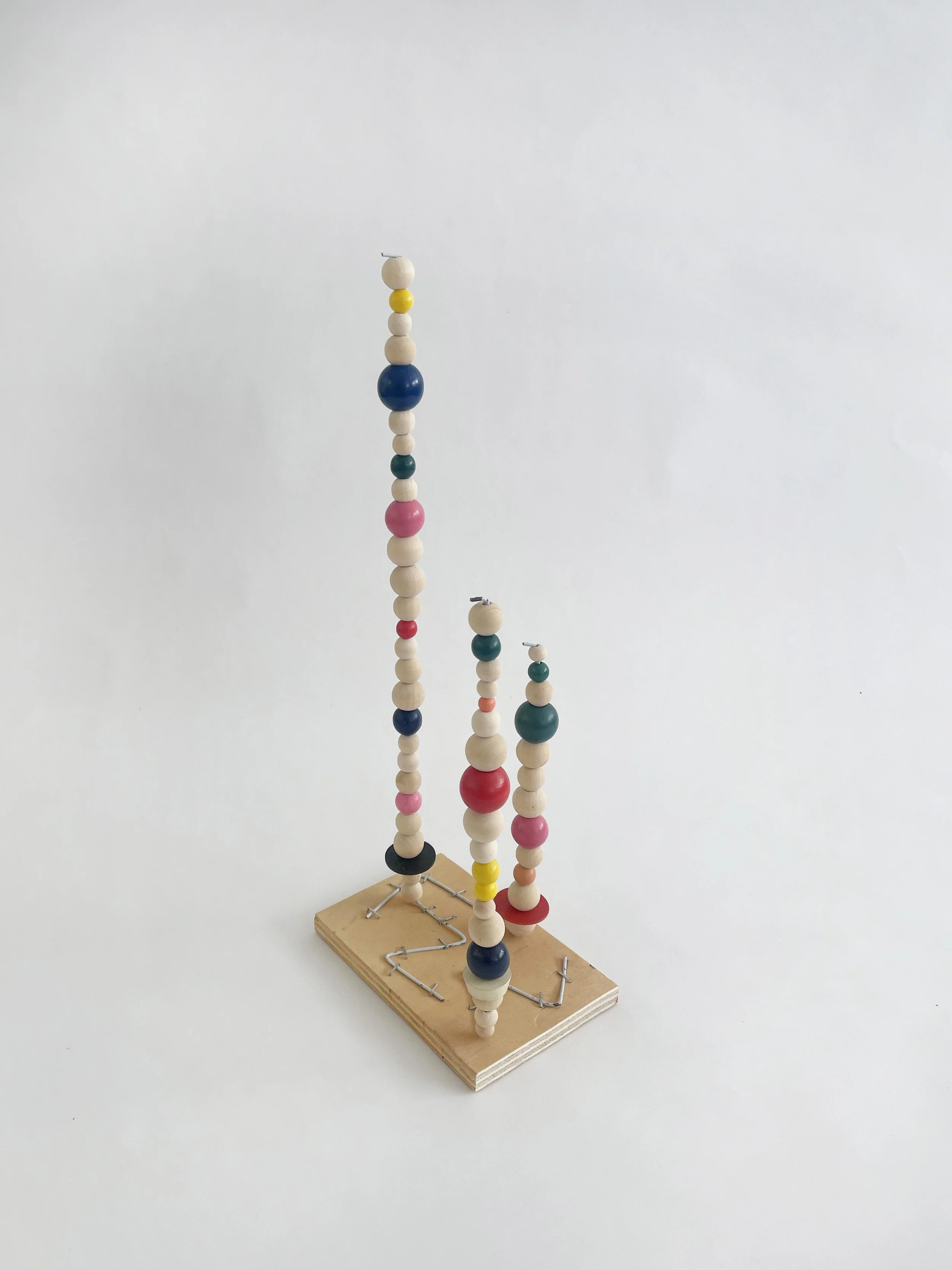 Untitled (watts tower), 2026, 16h x 6w 4d - natural and color wood beads, wire hangers, heavy duty staples, plywood, felt. 