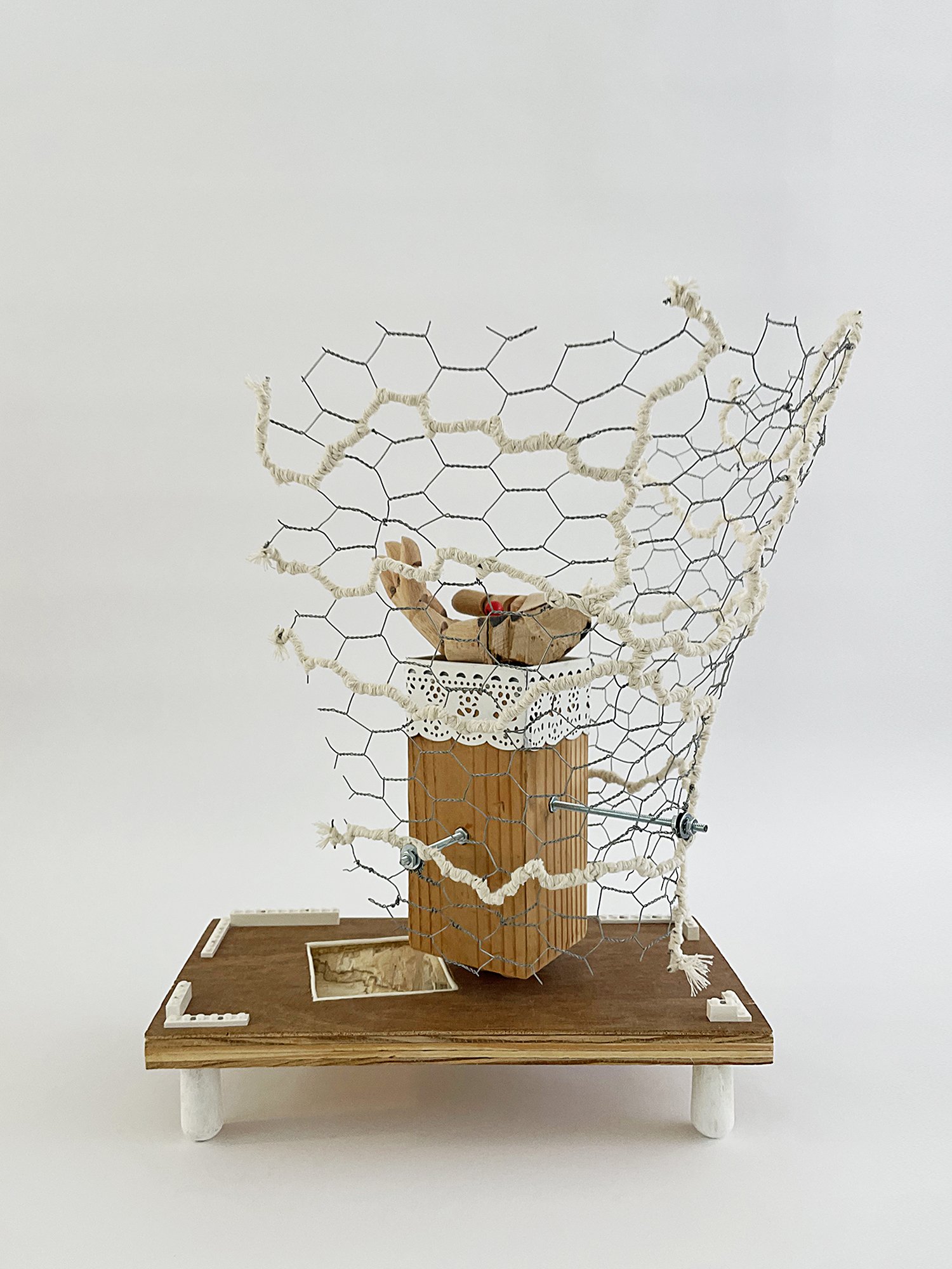 Untitled (Logan's Clock), 2025, 19h x 14w x 14d - salvaged plywood,4x4 lumber, walnut veneer, wood pegs {feet}, Ikea wooden model hand, chicken wire, butcher's string, Ikea metal trim, cotton fabric, threaded metal rod, wood beads, nuts, washers,