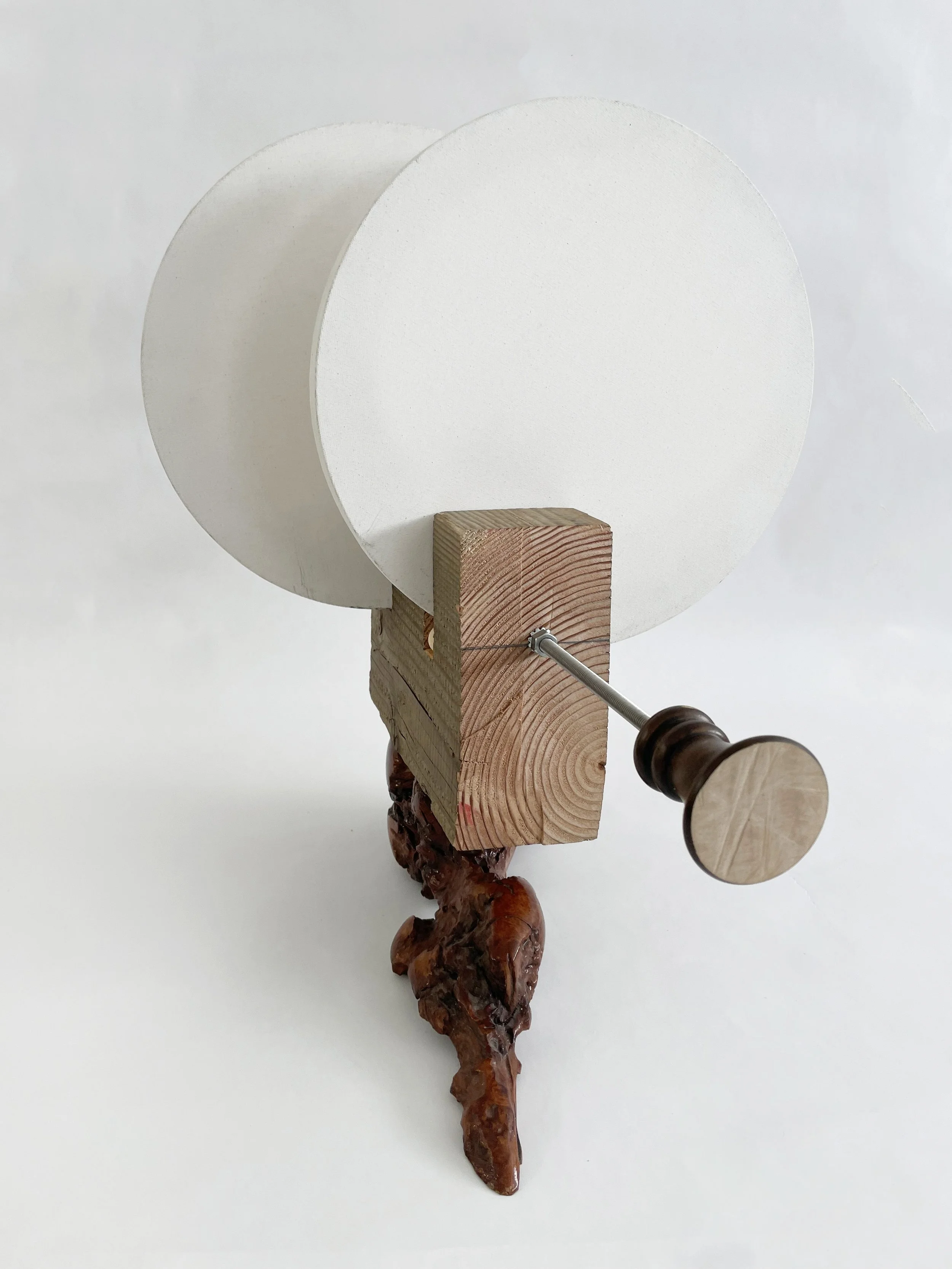 Untitled (two disks) 2025- 2026, 19.5h x 16w x 22d - thrift store resin coated driftwood, 3x7 construction timber, threaded rods, lock nuts, 2 pre-primed round stretched canvas, wood finials, dowels, wood beads.