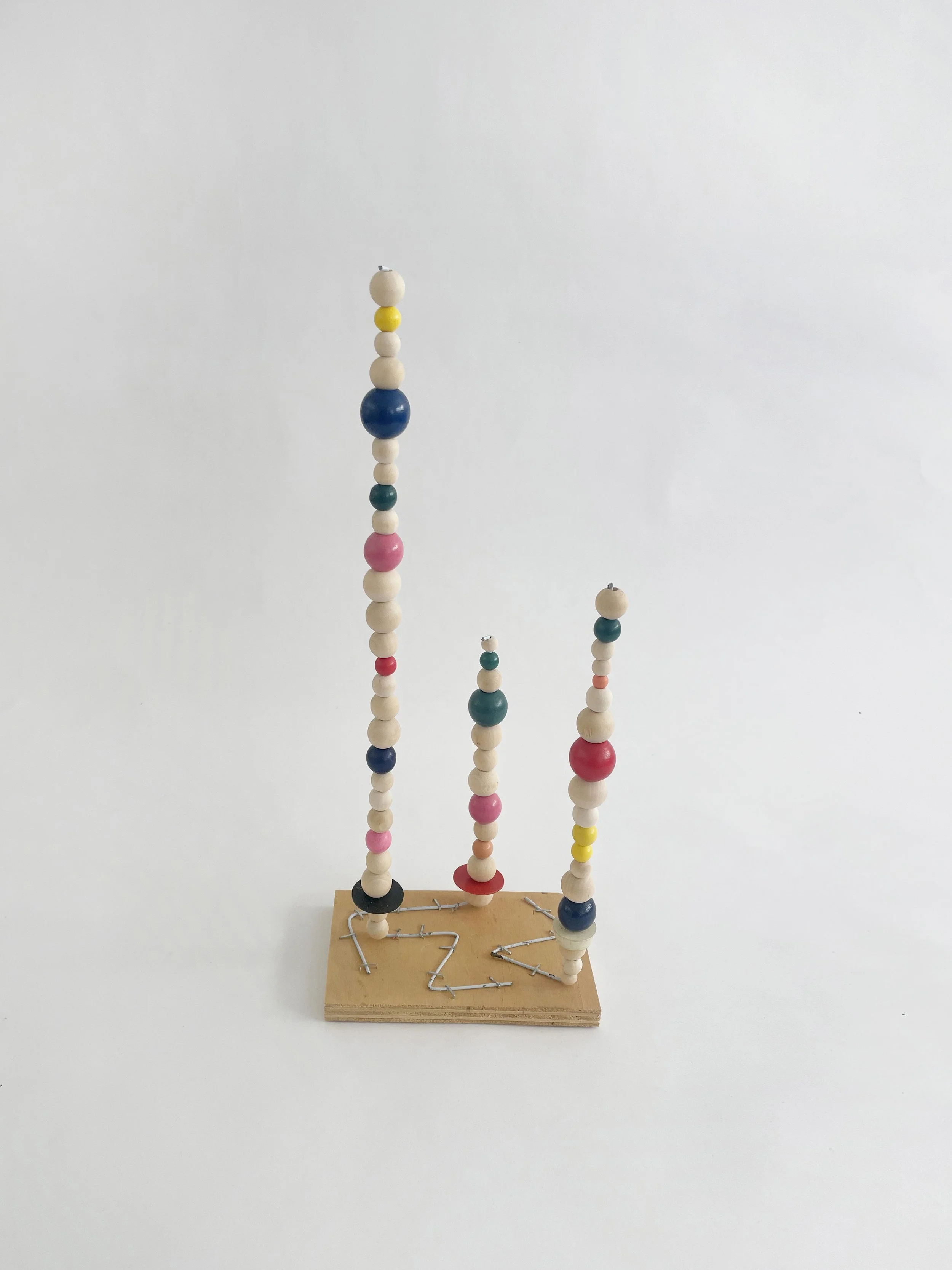Untitled (watts tower), 2026, 16h x 6w 4d - natural and color wood beads, wire hangers, heavy duty staples, plywood, felt. 