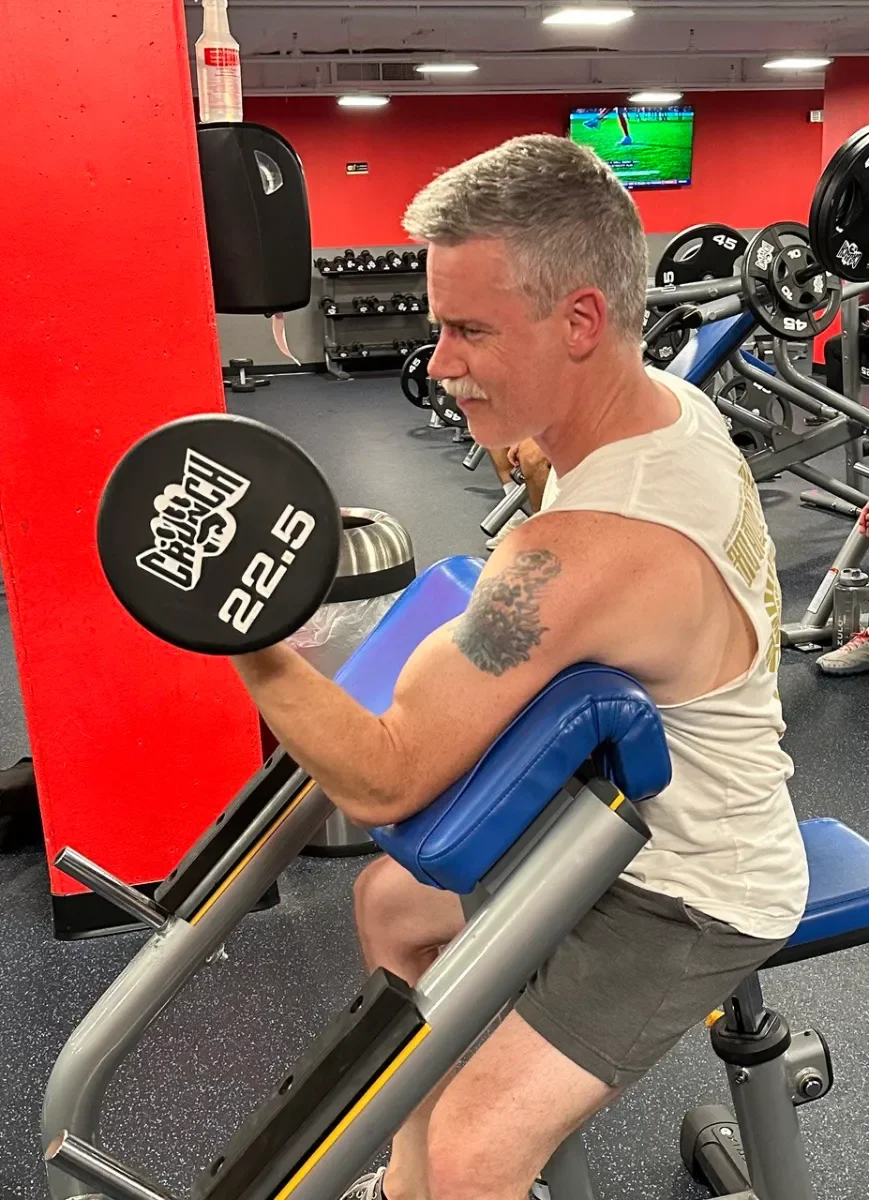 A mature father lifting dumbbells in a basement home gym