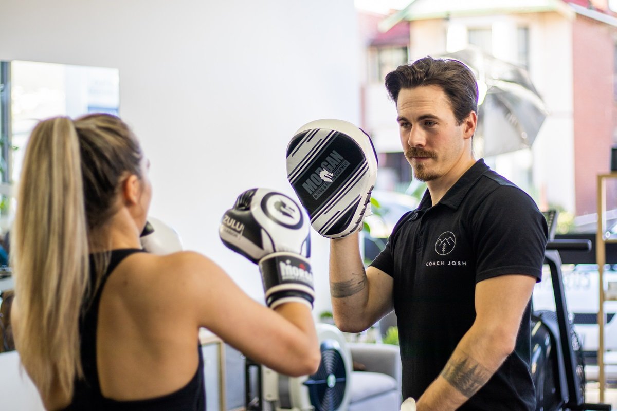 Coach Josh teaching a mother boxing.