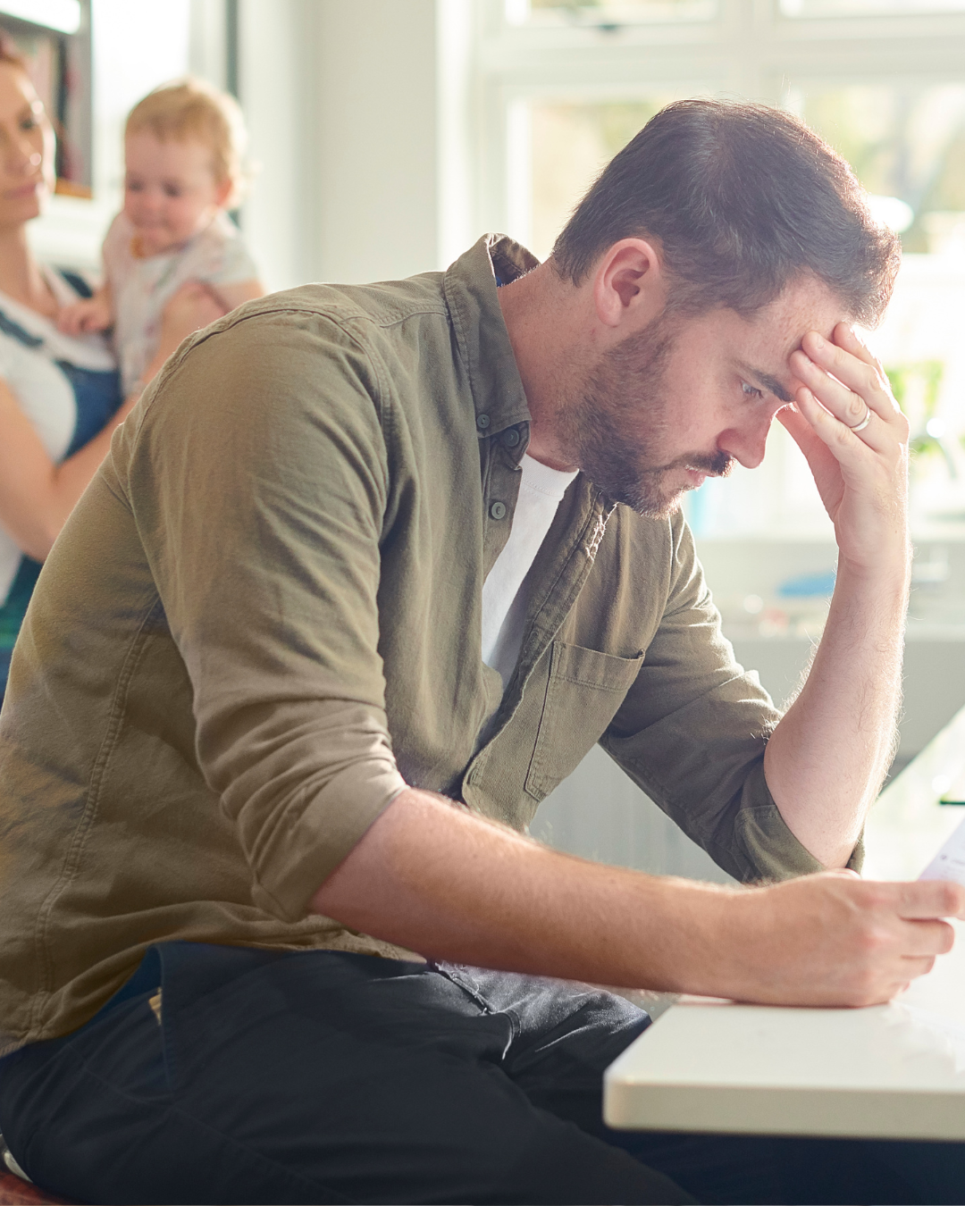 A stressed out dad with his family at the kitchen counter.