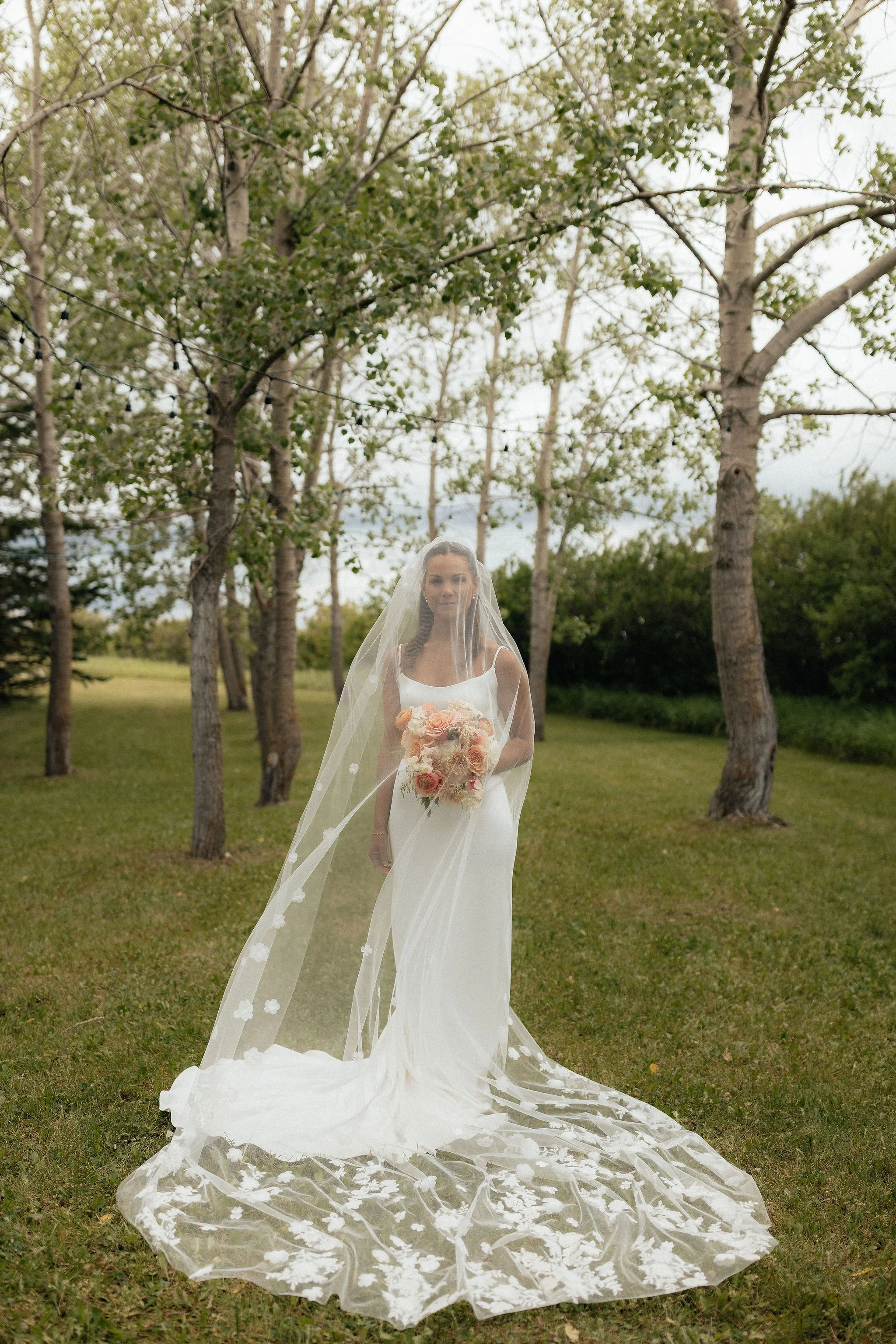 A bride in a white wedding dress in a forest, at a wedding venue near Calgary, Alberta.