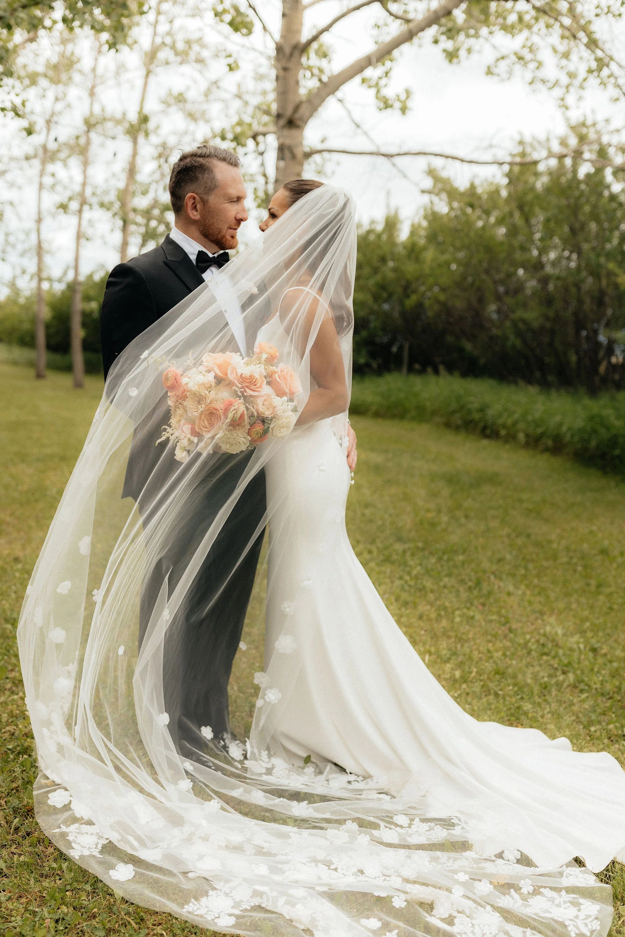 A bride and groom standing close together outdoors, at a Calgary wedding venue.
