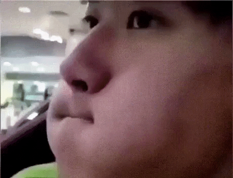 Close-up of a person's face with a slight smile, looking to the side, in an indoor setting.