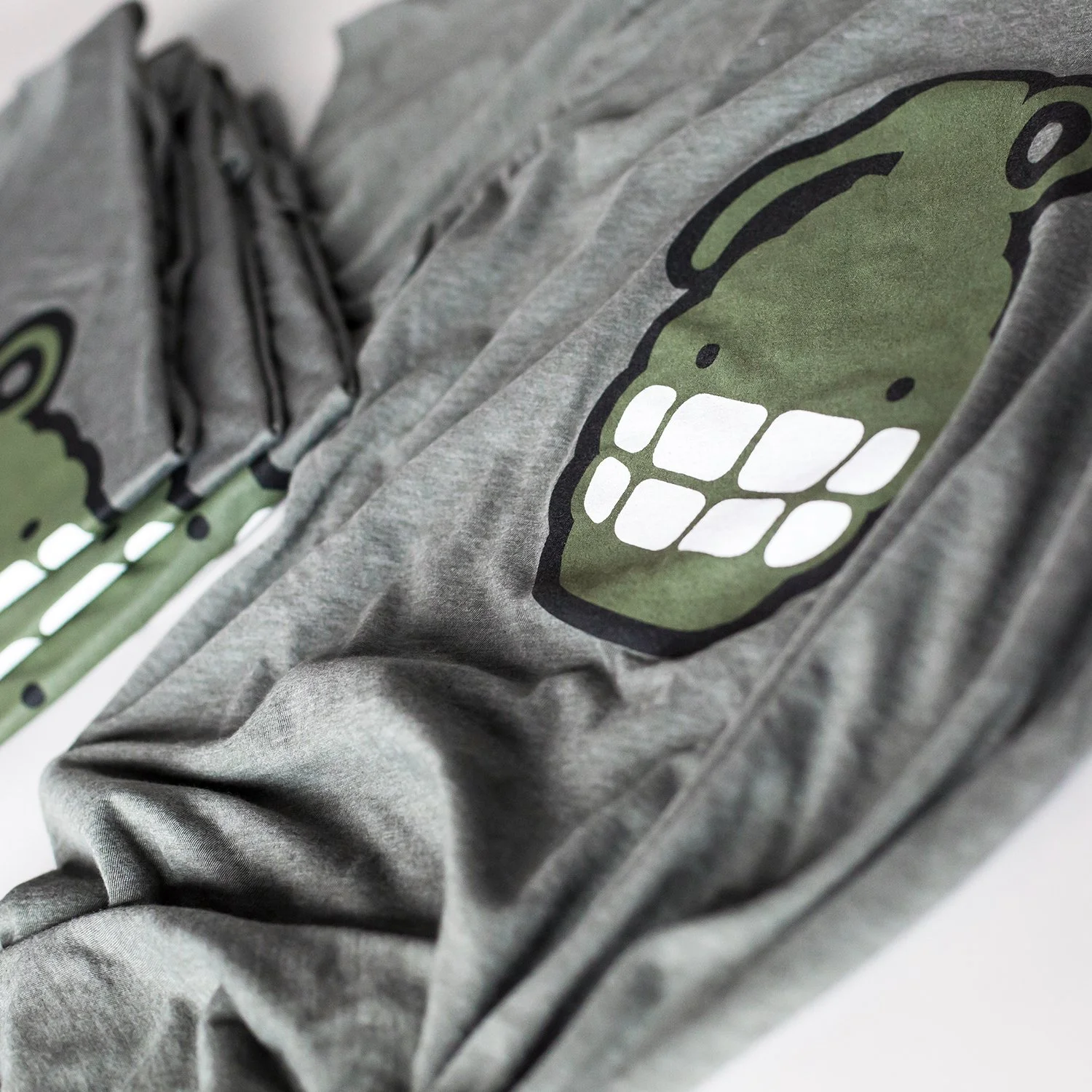 Grey hoodie with a printed graphic of a green skull with white teeth and black outline.