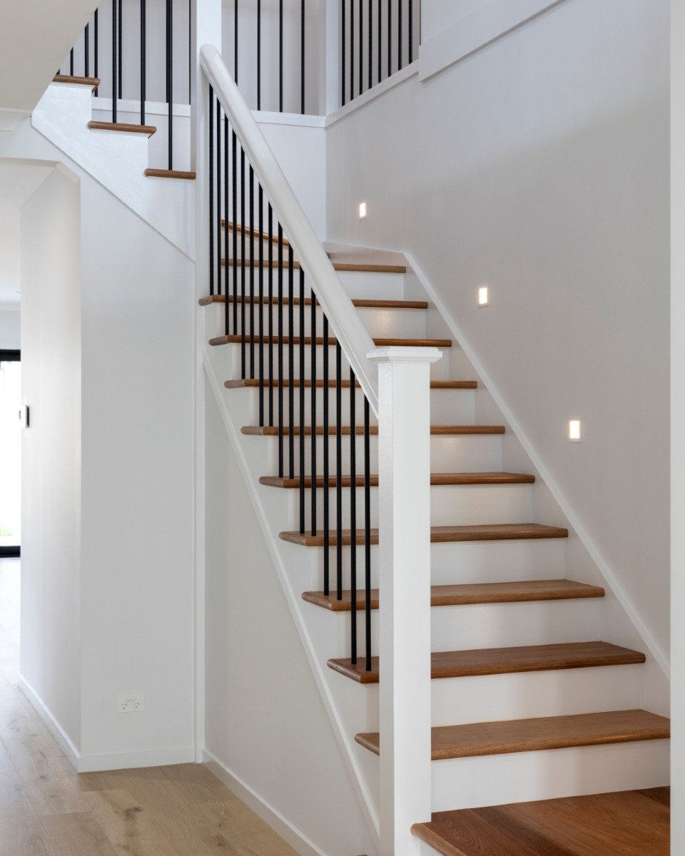 A staircase that elevates both design and wellbeing. 🔨 Designed with precision, its L-shaped layout maximises space and offers an elegant feature with natural timber treads, sleek black balusters, and crisp white finishes. The recessed LED lighting 