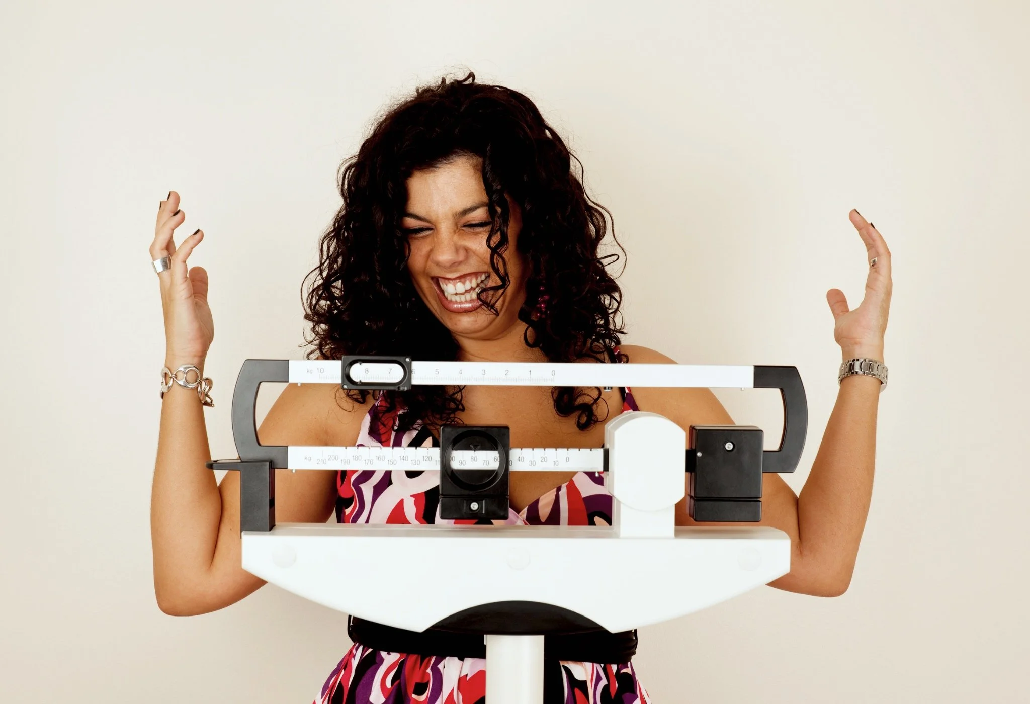Latin woman standing on scale excited about weight loss.