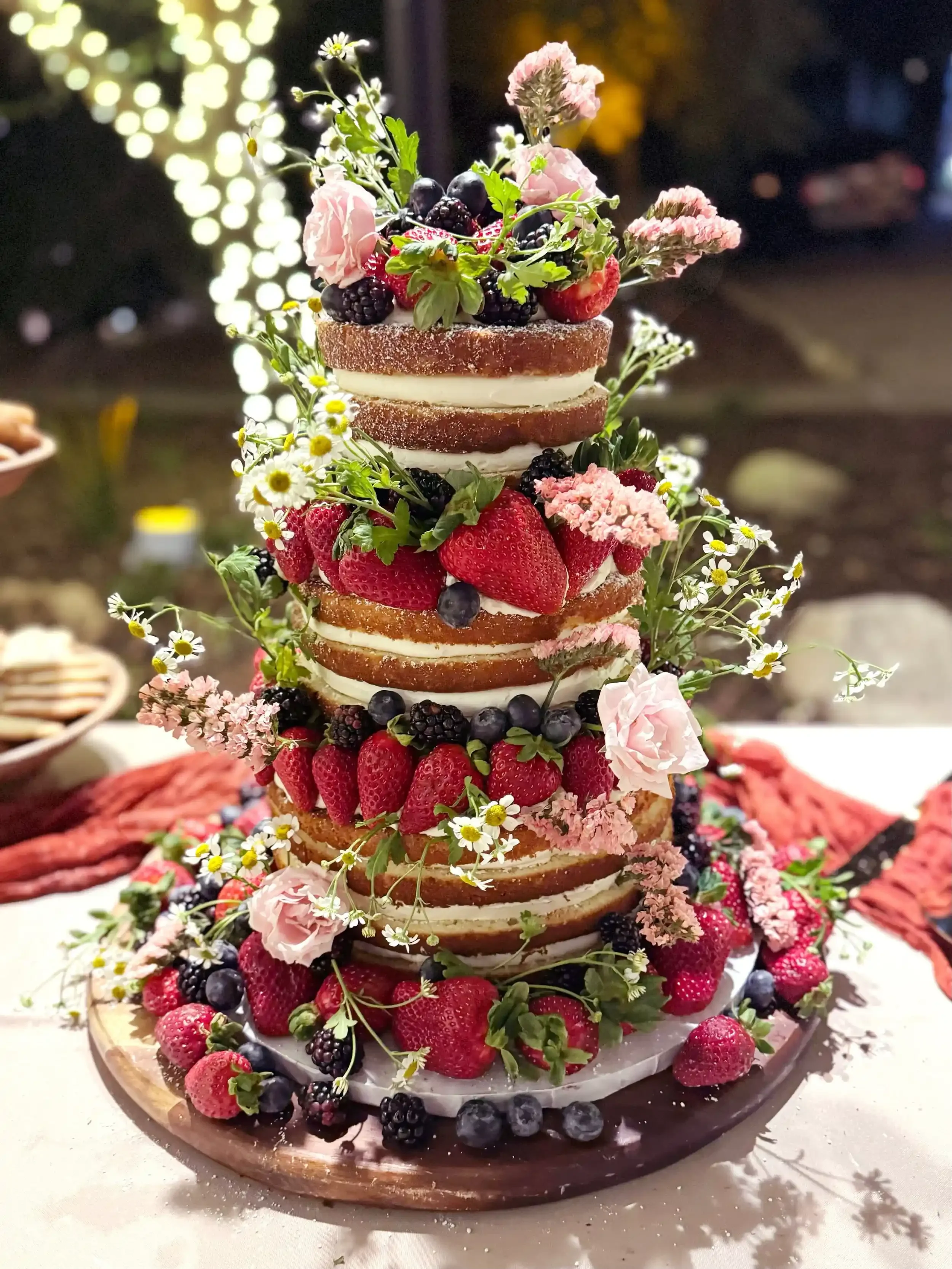 Custom 3-tiered floral naked wedding cake with strawberries, blueberries, and blackberries