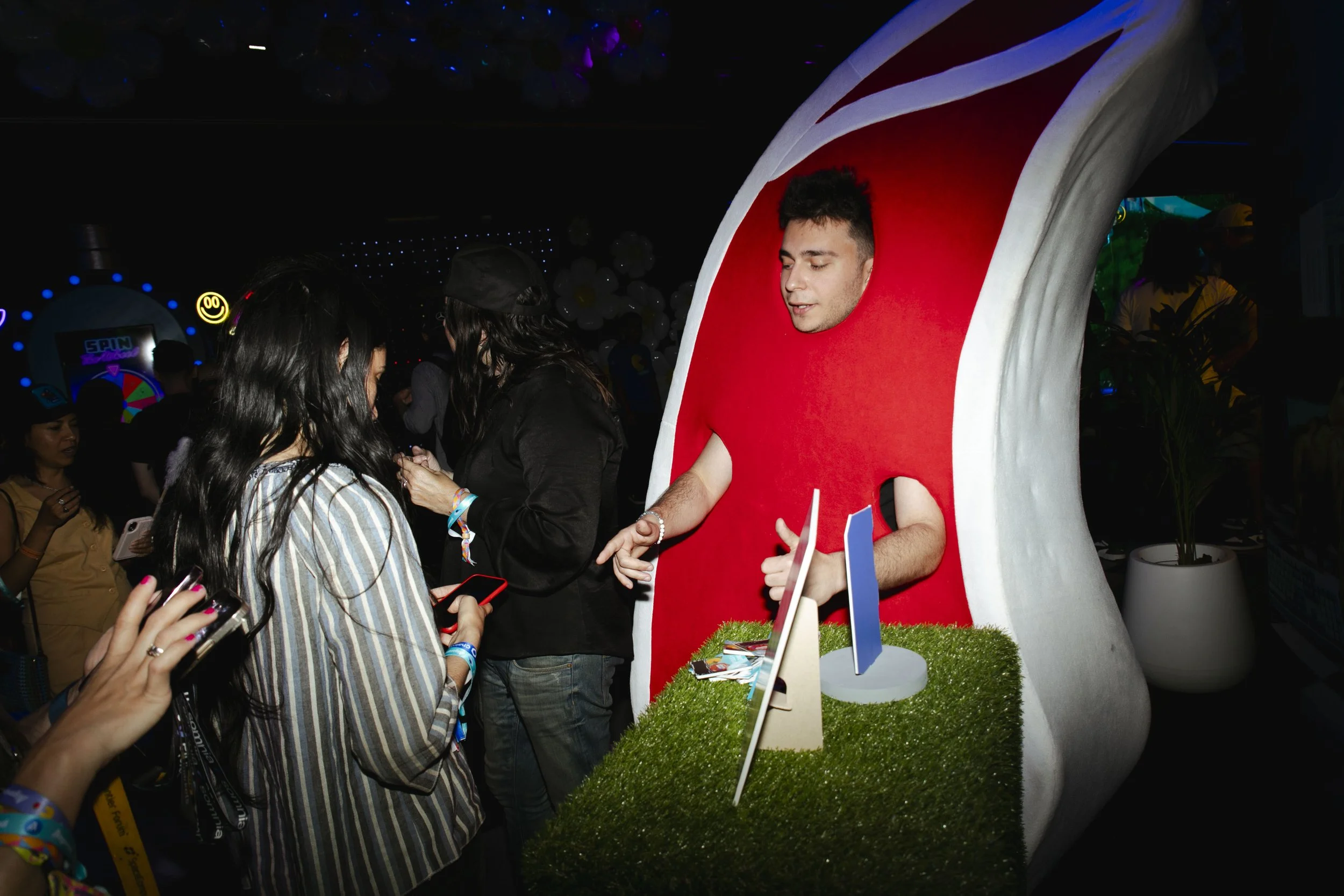 A person dressed in a Oreo cookie costume standing behind a booth at a crowded event, interacting with festival attendees.