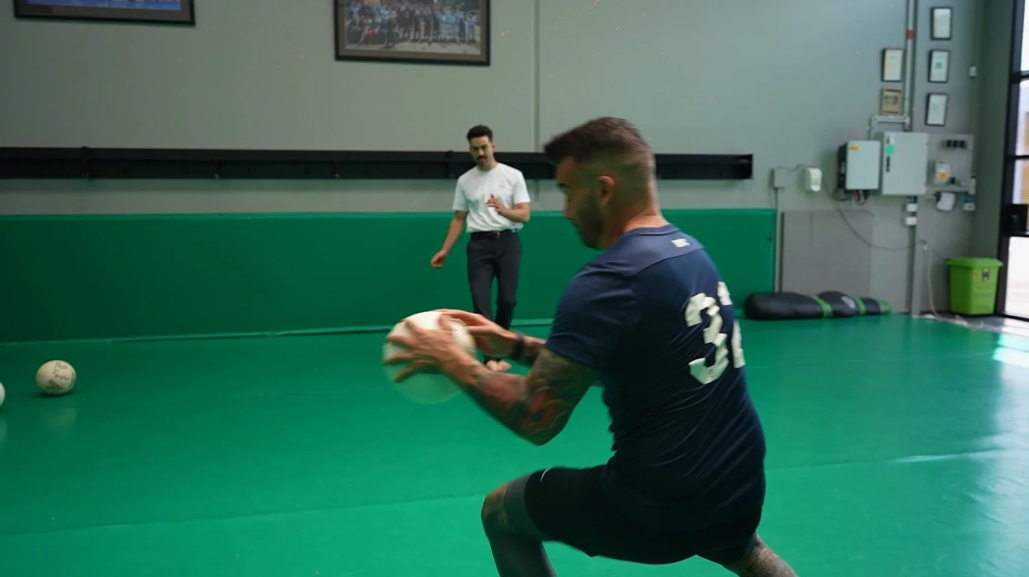 Soccer player doing a lunge and catch drill on turf during rehab