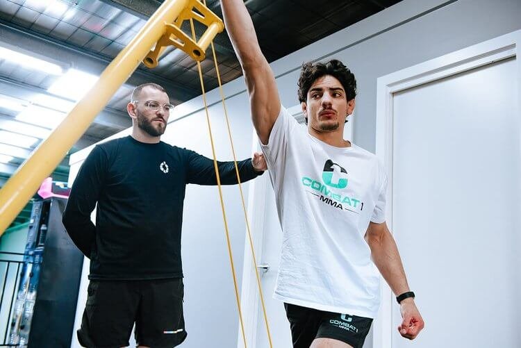Athlete performing a shoulder mobility exercise supervised by an osteopath