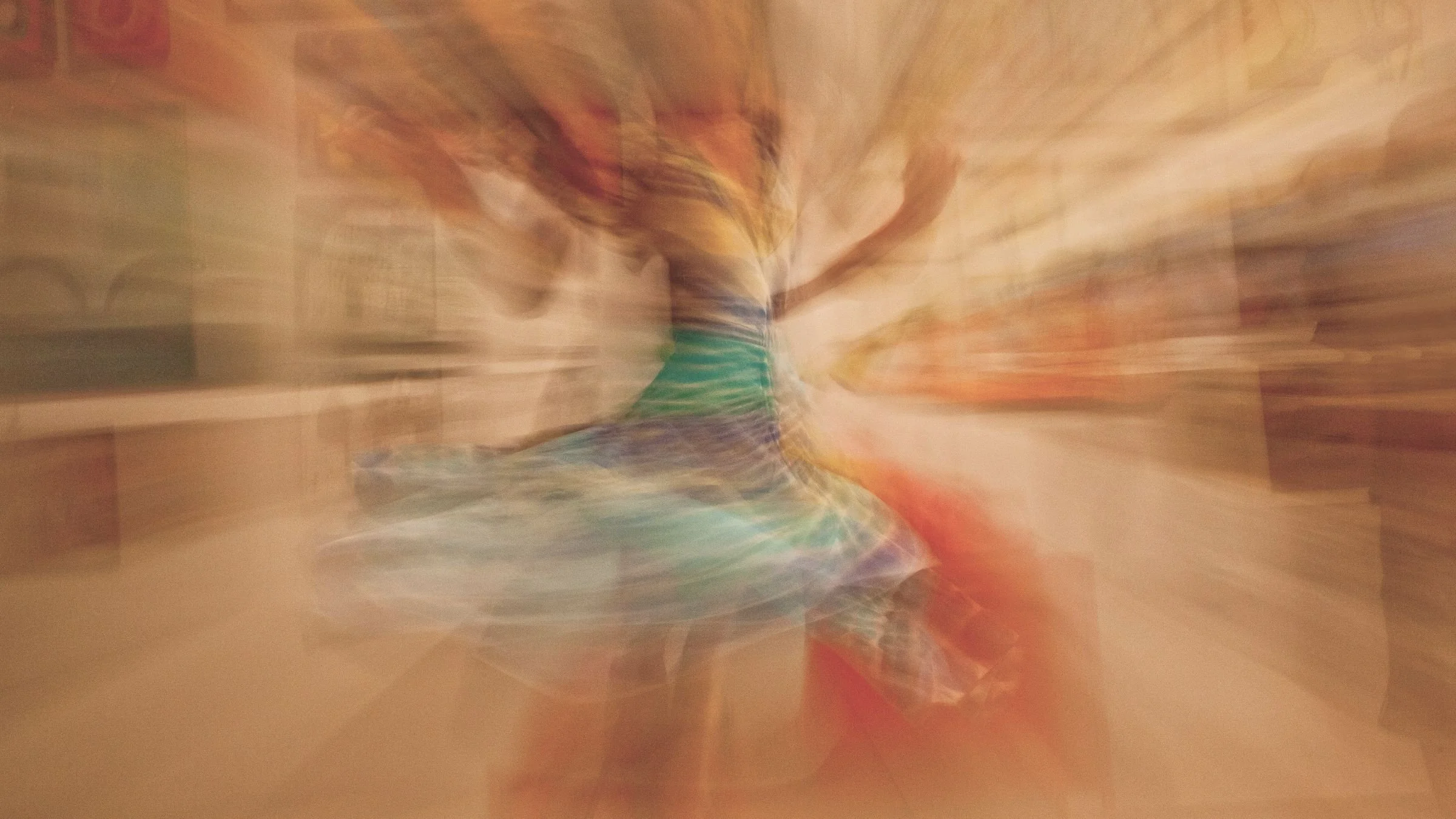 Une personne en mouvement, portant une robe colorée, dans une pièce avec un décor chaleureux. L'image est floue en raison d'un mouvement rapide.