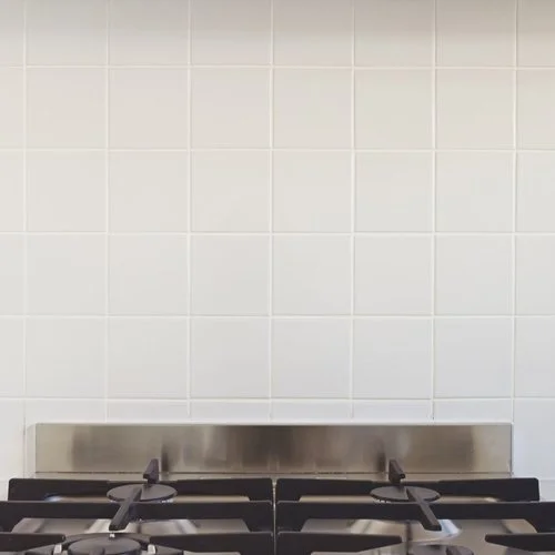 Stainless steel backsplash and black gas stove with metal grates in a kitchen