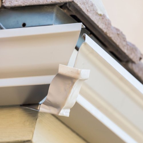 Close-up of a white exterior gutter system with a downspout extension.