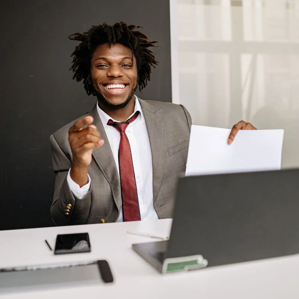 A black male in a suit completing off-the-job training hours in apprenticeships with an assignment at his computer