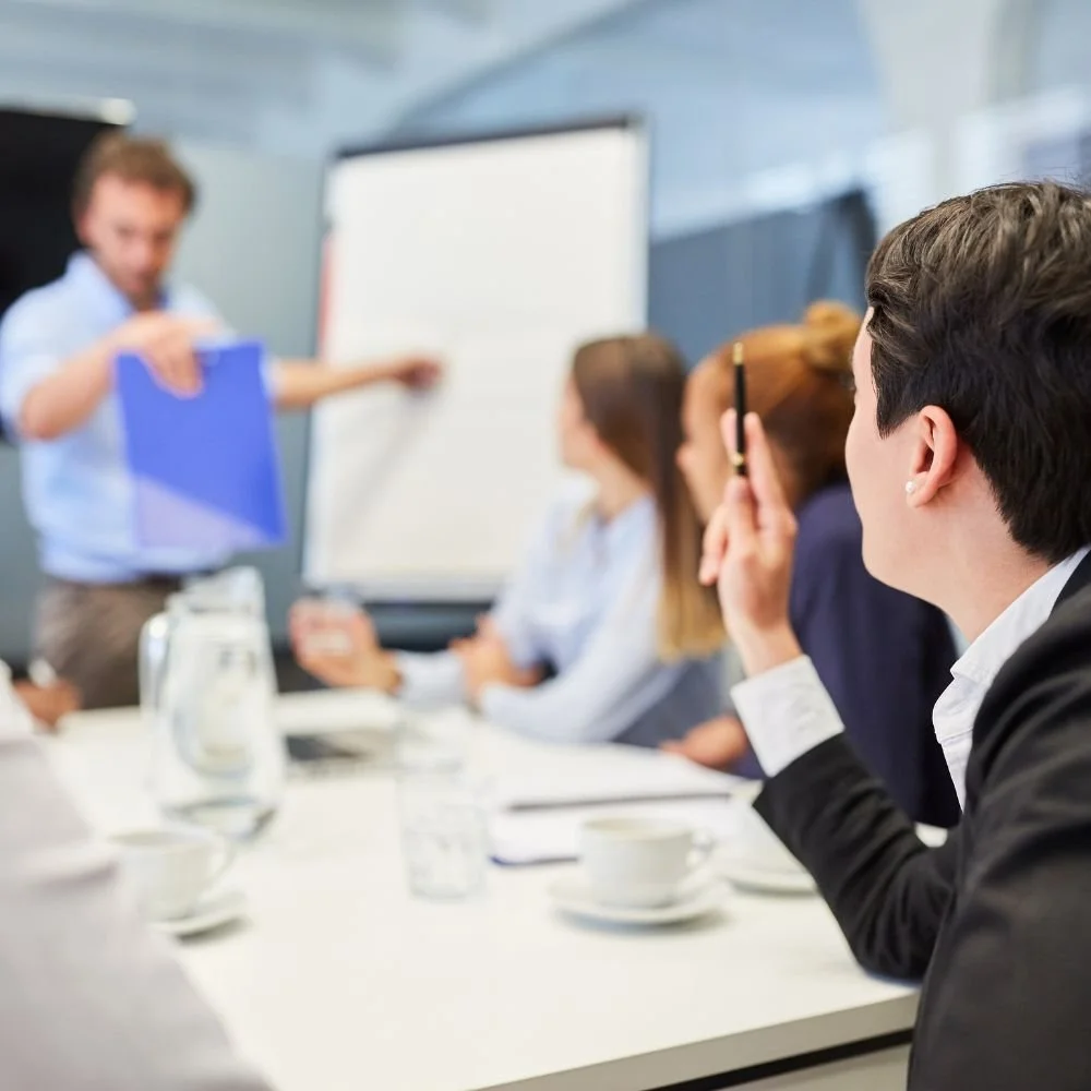 Off-the-job training at a workshop, teaininer pointing to whiteboard, candidates sitting around a table