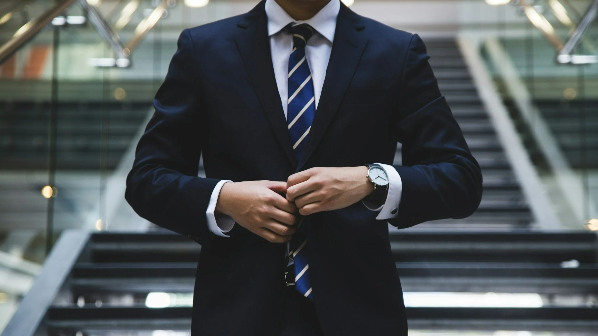 Job hunting tips for graduates - close up of a white male doing up his navy suit jacket