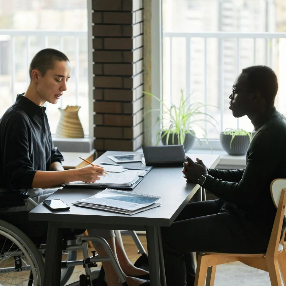Male in wheelchair on the HR Support apprenticeship in a meeting with a male staff member
