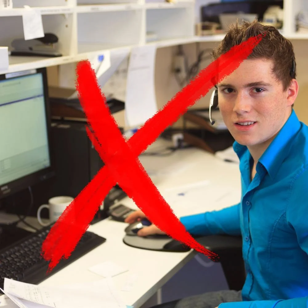 A young male working at a computer in an office with a red cross through the image for Apprenticeship Myths