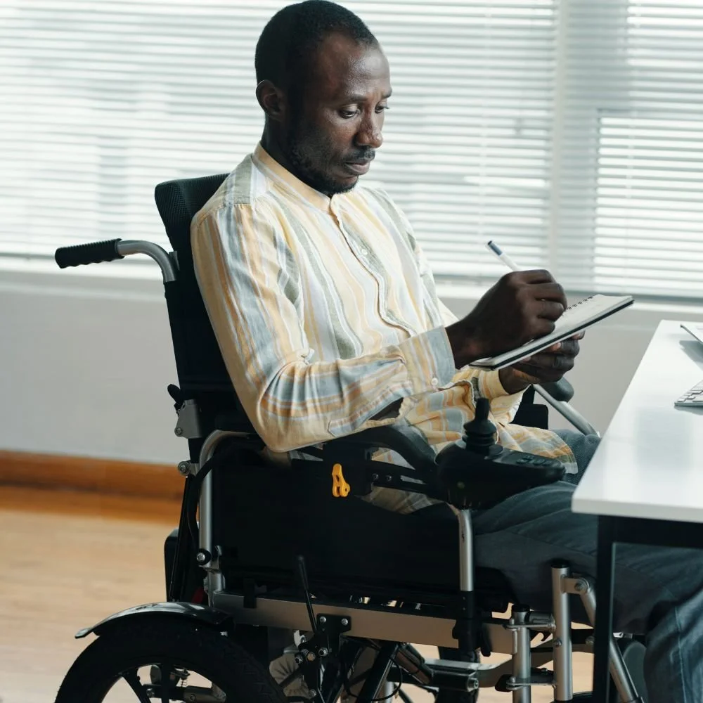 Black male in a wheelchair, at a desk on the Business Administrator Apprenticeship
