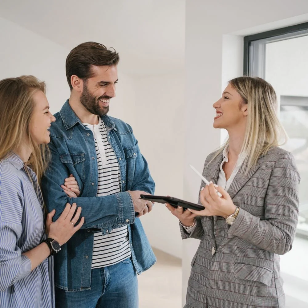 A young blonde business female is talking to a couple in a house on her Junior Estate  Agent Apprenticeship