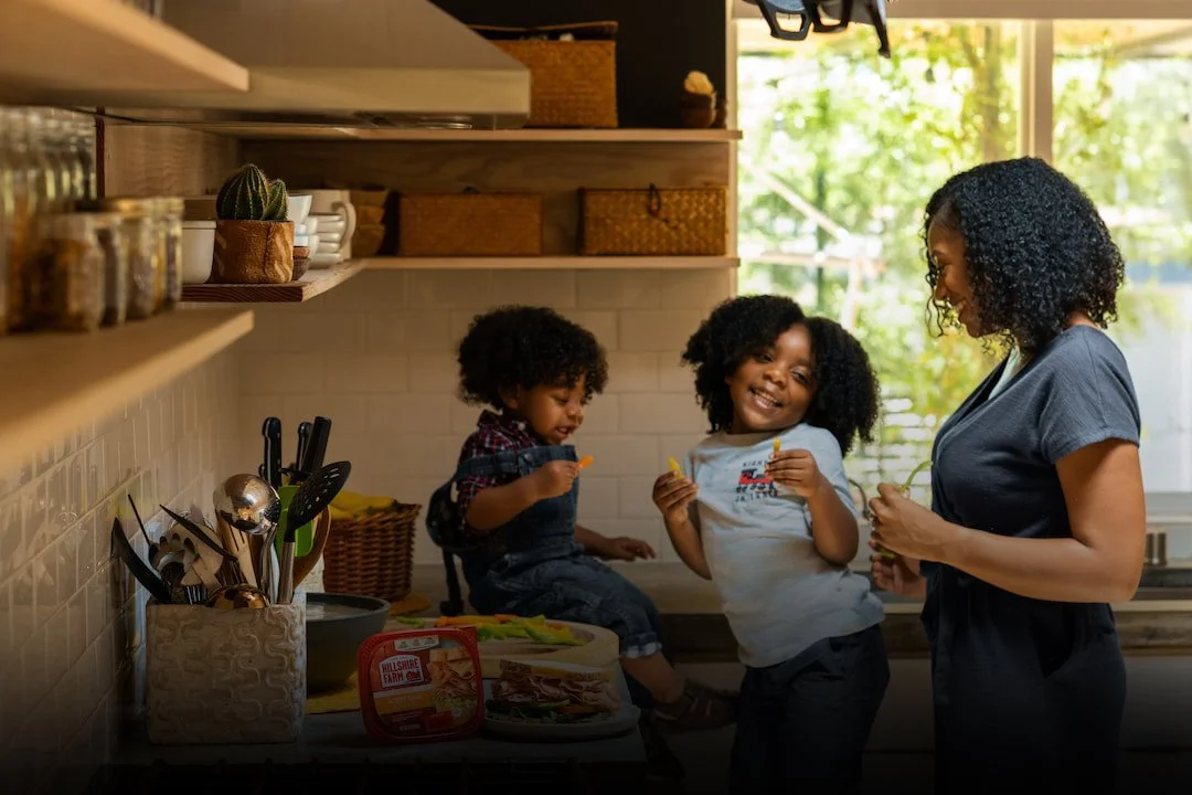 Our Values consider family seen here as a black mum and her 2 children in a kitchen