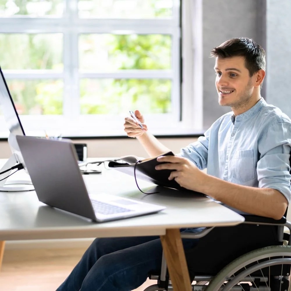 Young gentleman, in a wheelchair at a computer desk on an Administration Assistant apprenticeship