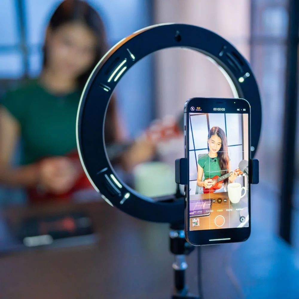 Content Creator apprenticeship, a content phone holder showing the girl it is recording, playing a ukulele