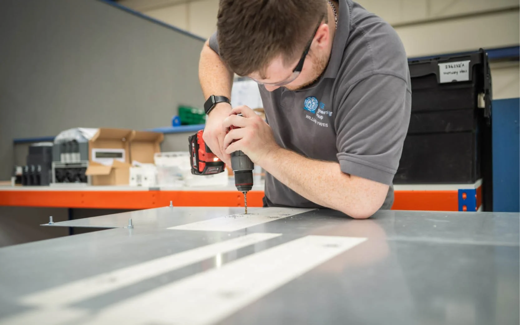 An apprentice drilling into a metal sheet