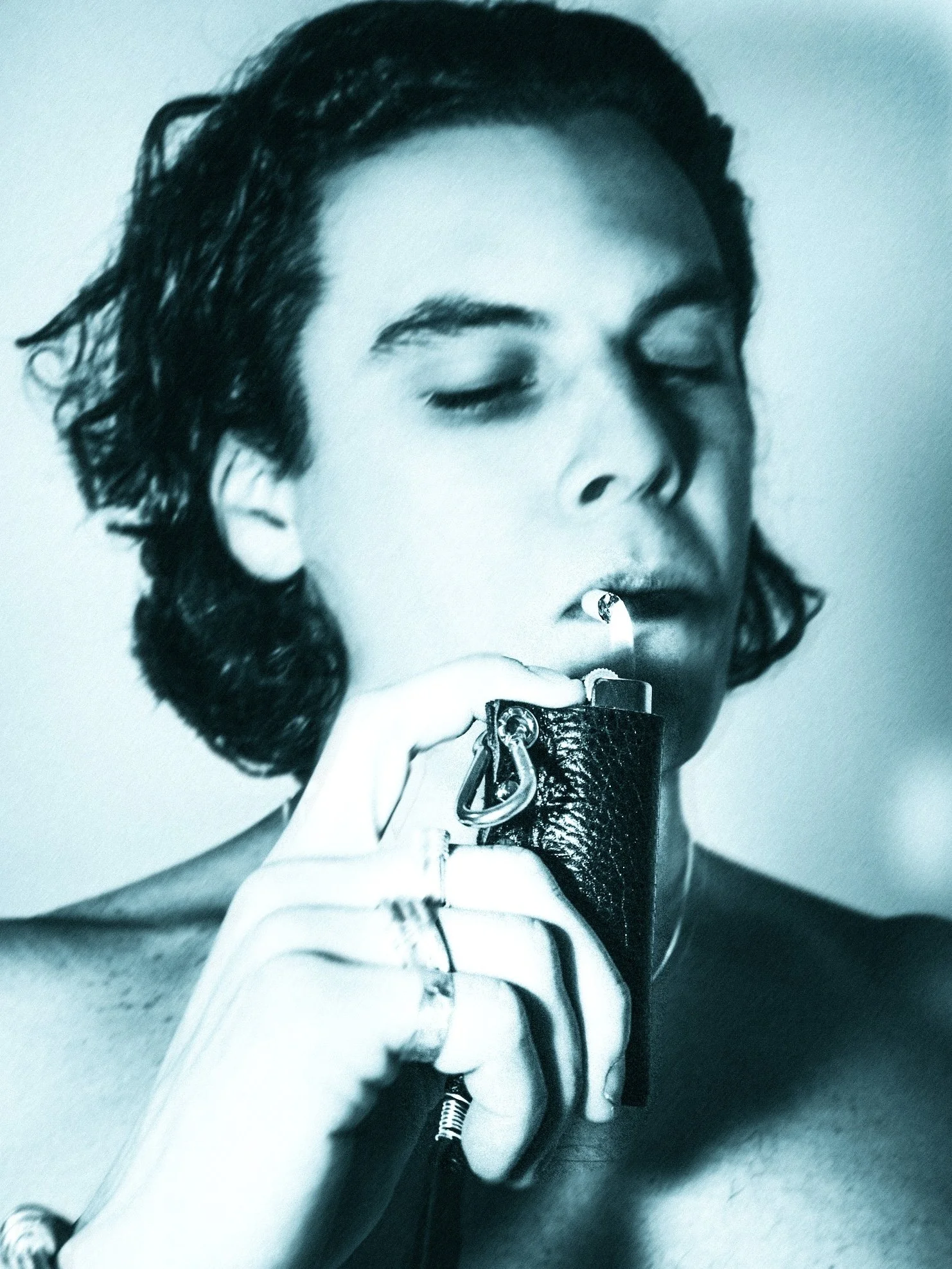 Close-up of a man with dark hair, wearing multiple silver bangles on his arm, touching his forehead with his fingers, and looking into the camera.