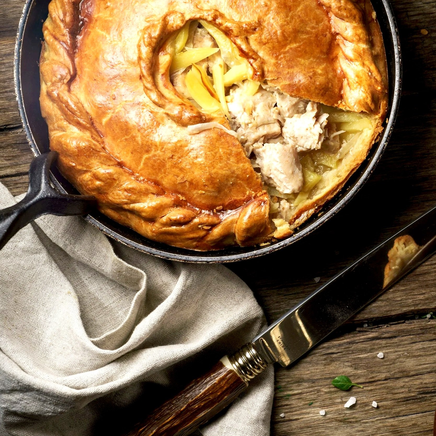 Chicken pie in a dish with a cloth and knife