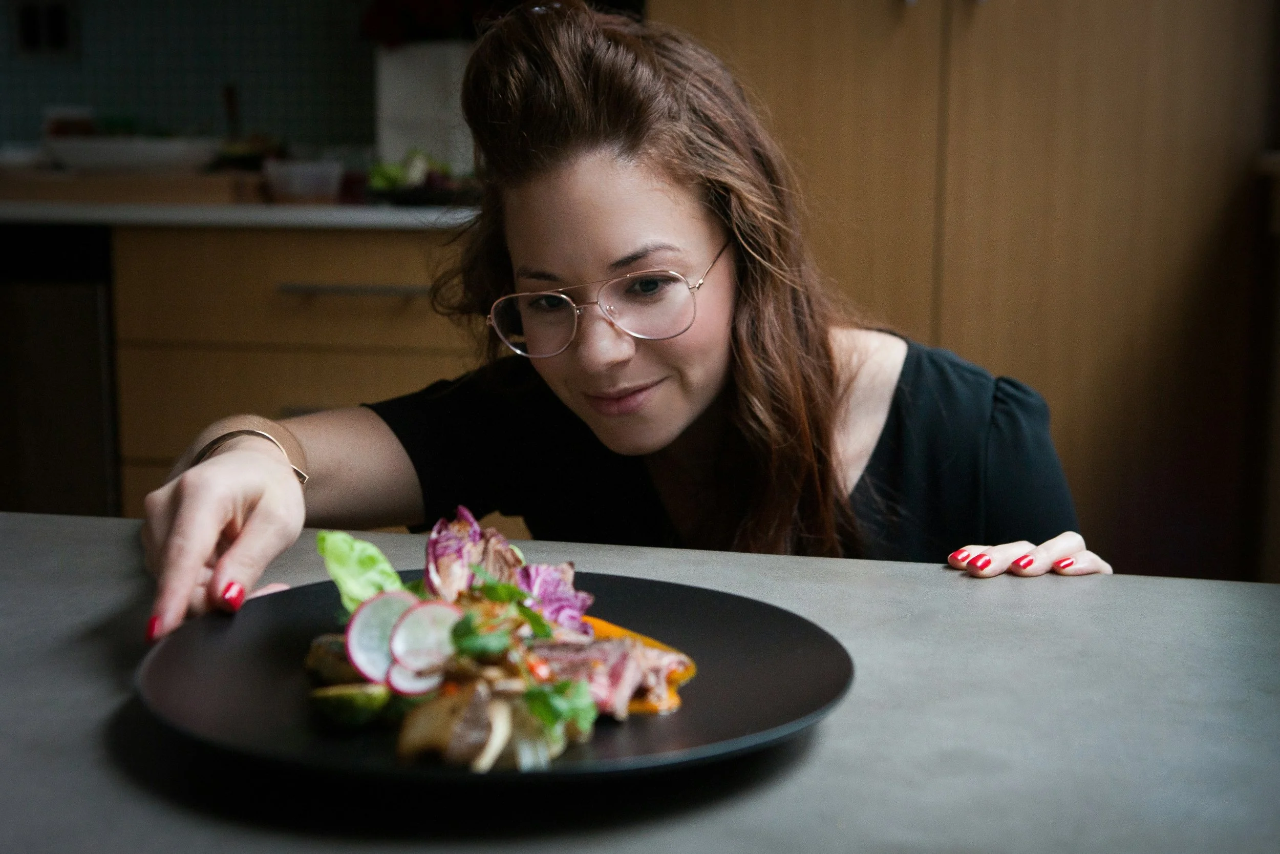 A woman looking at a find dining plate of food