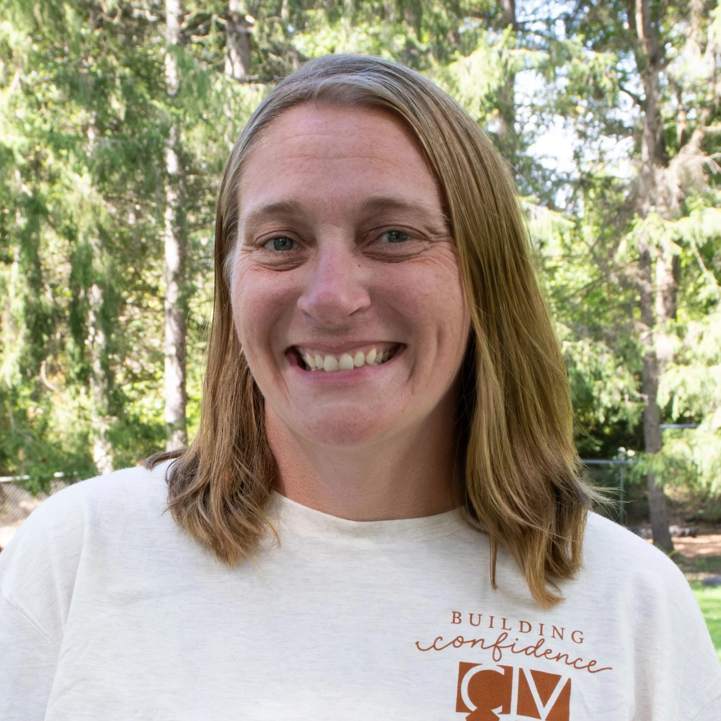 Smiling woman with shoulder-length light brown hair wearing a leopard print top.