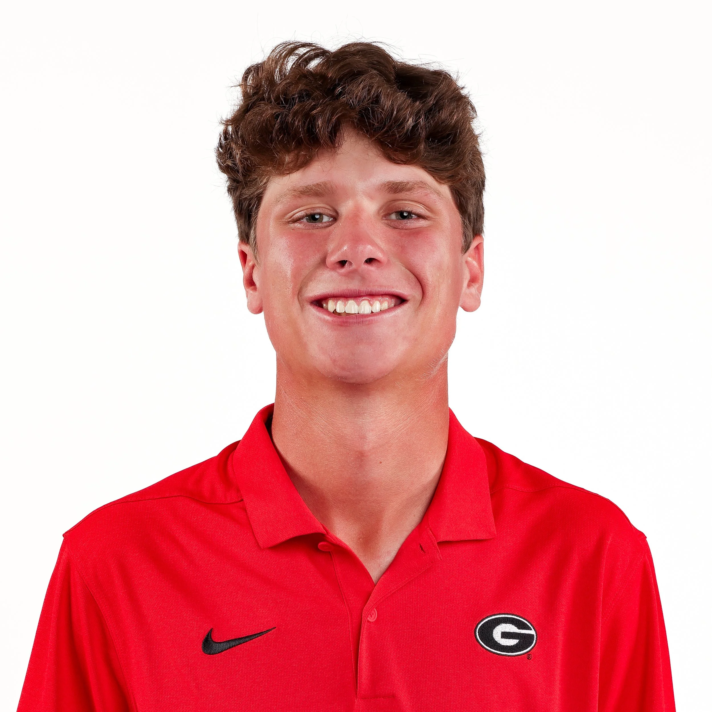 Close-up of a young man wearing a red sports jersey with the University of Georgia logo, smiling, against a white background.