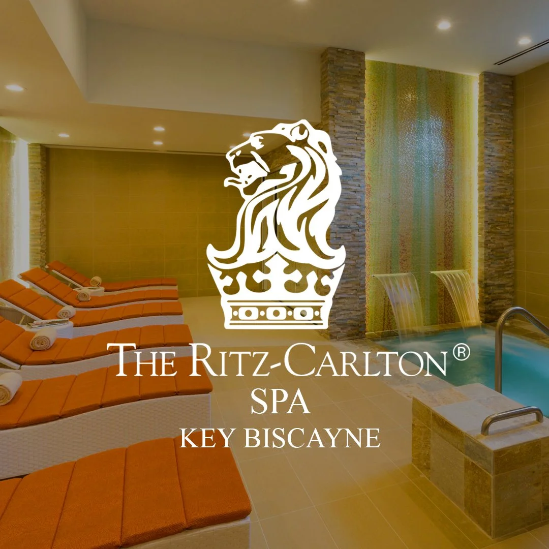 Indoor spa area at The Ritz-Carlton Key Biscayne, featuring lounge chairs with orange cushions, a small pool with water features, and a modern design with stone accents.