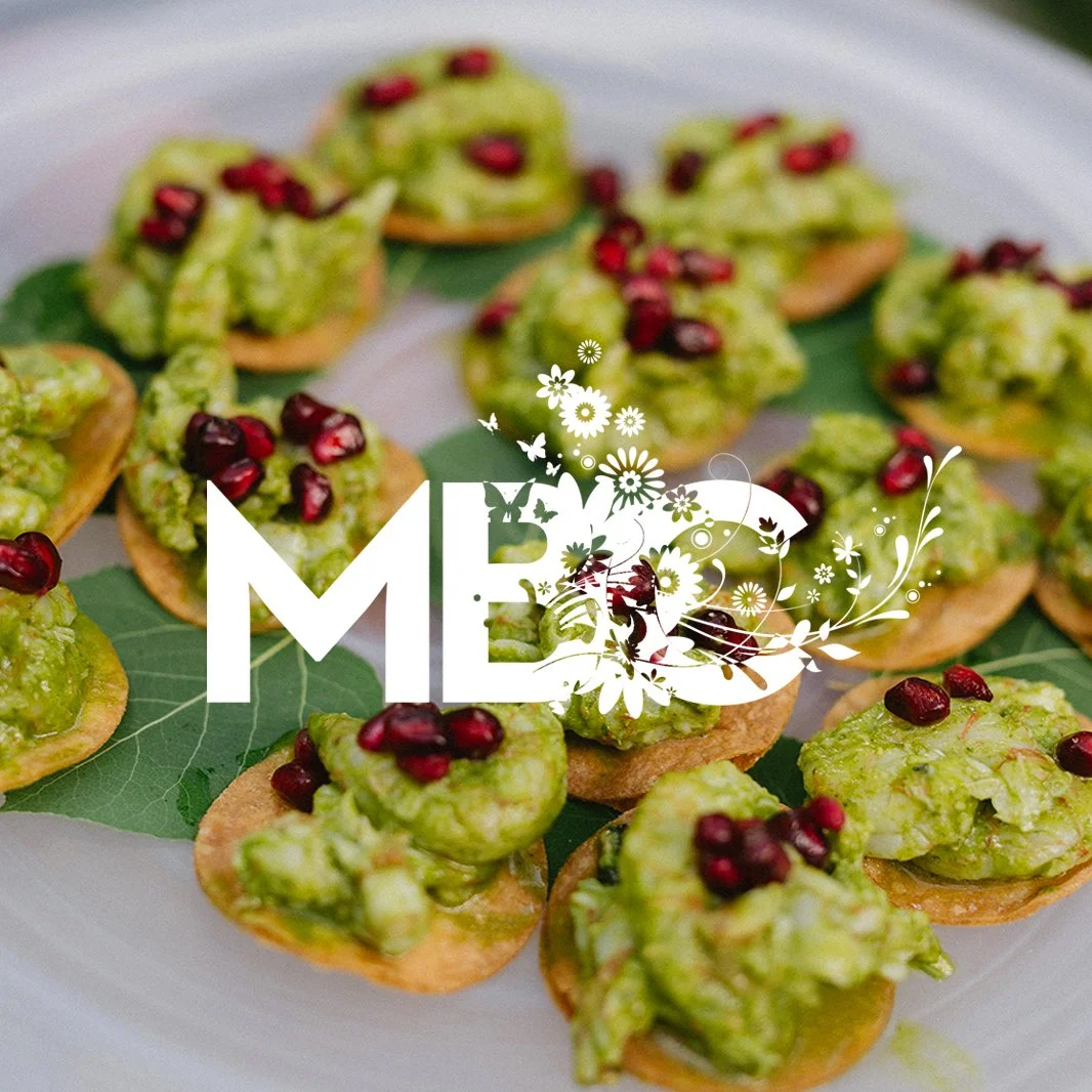 Appetizers with green spread topped with pomegranate seeds on a platter.