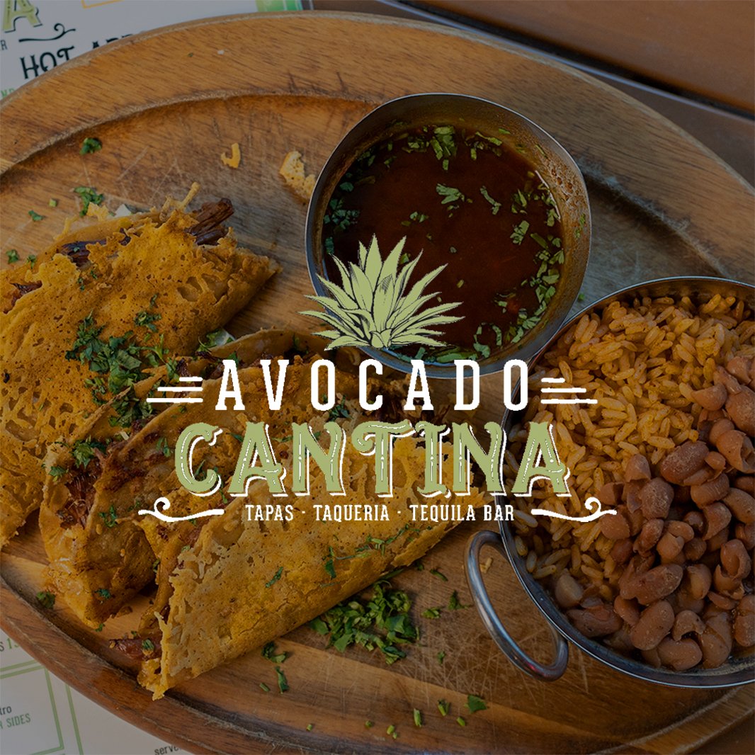 Mexican dish with tacos, beans, rice, and sauce on a wooden plate at Avocado Cantina.