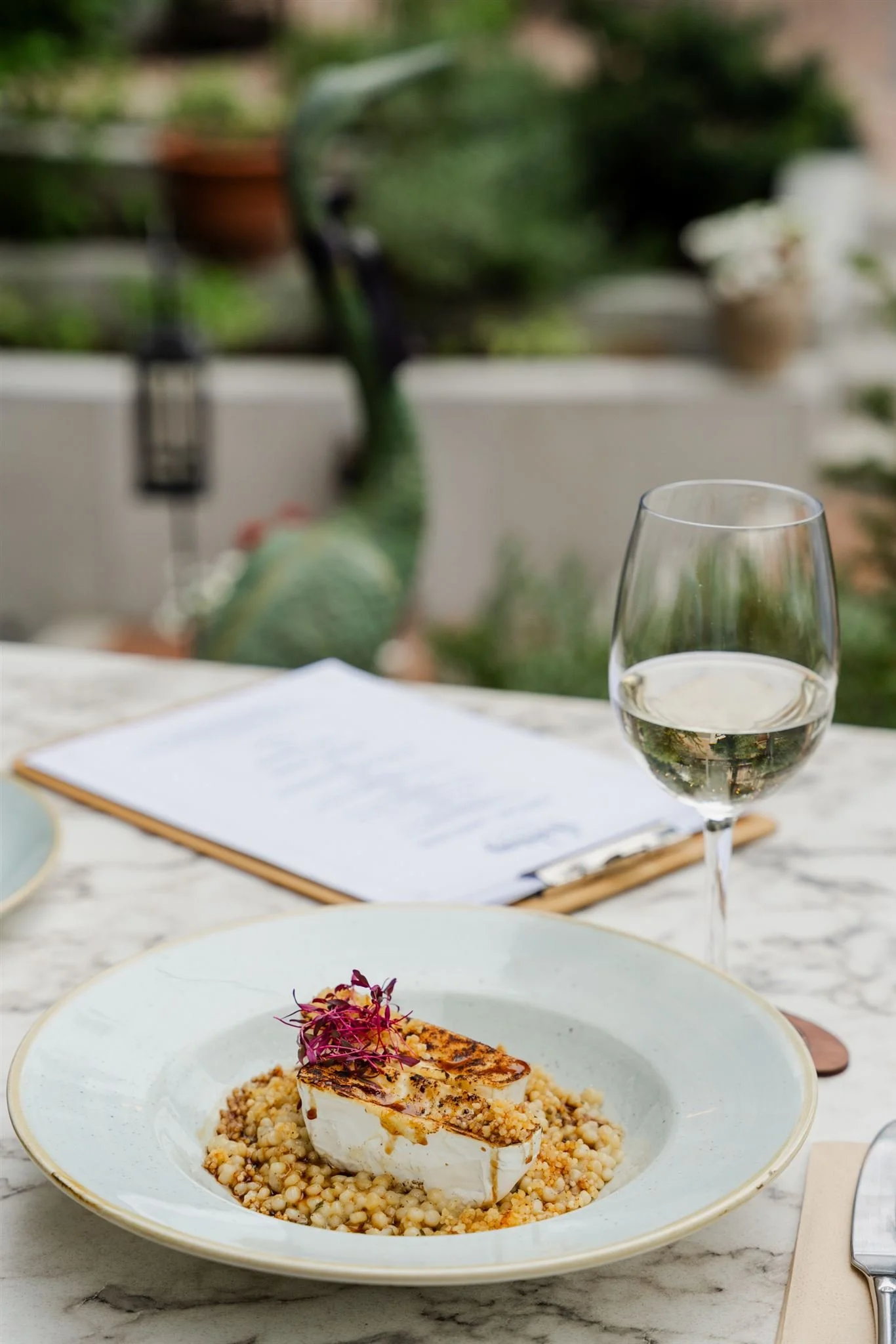 Roasted camembert with tarragon egg barley risotto and a glass of chilled white wine on the cozy terrace of Andrássy Garden.