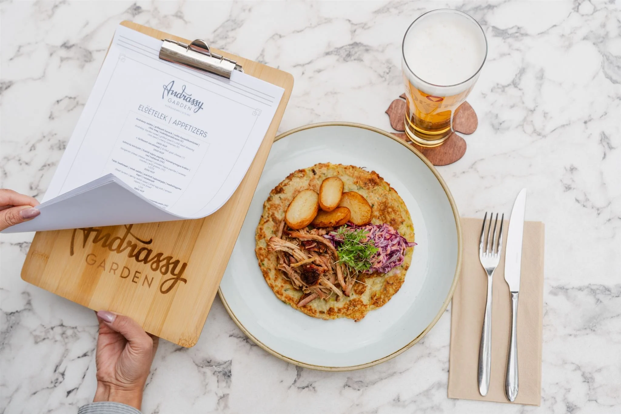 Smoked pulled pork on zucchini fritters with fresh coleslaw, the seasonal menu, and a glass of cold Hungarian draft beer.